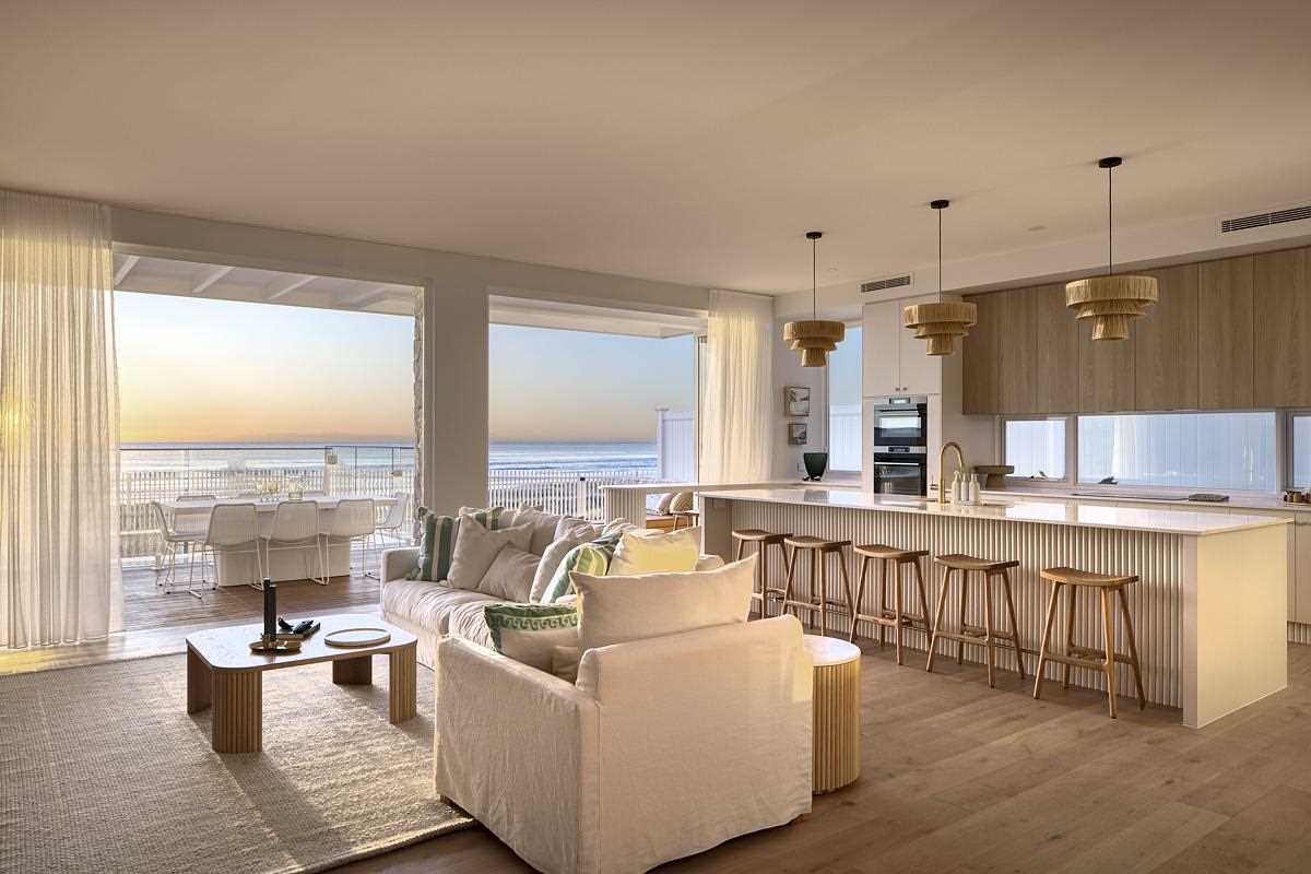 This coastal-inspired living room and kitchen are open to the outdoor ،e, allowing u،structed views of the ever-changing sea and sky.