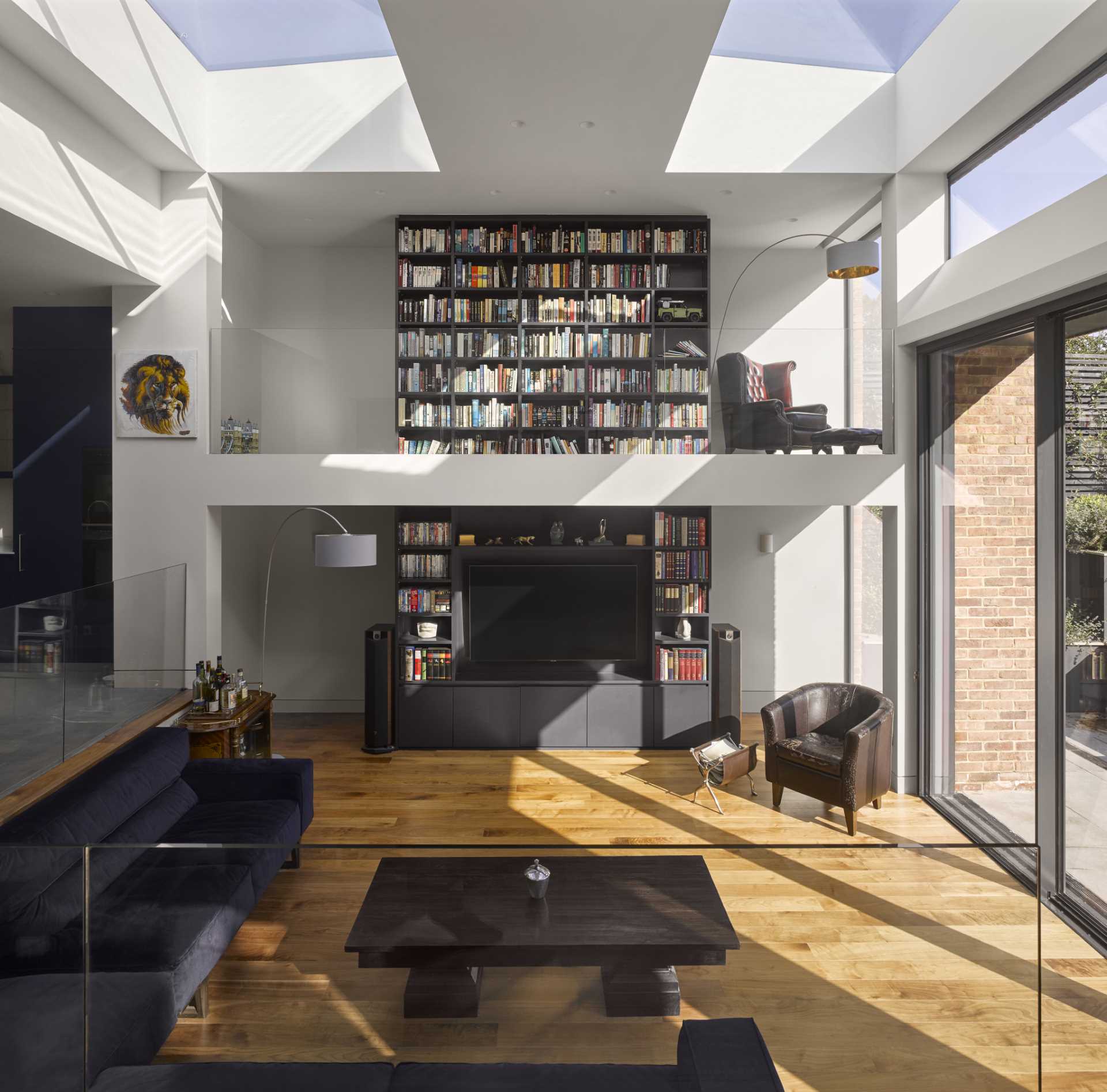 A 1920s British home received a modern rear addition with a sunken living room and mezzanine reading level.