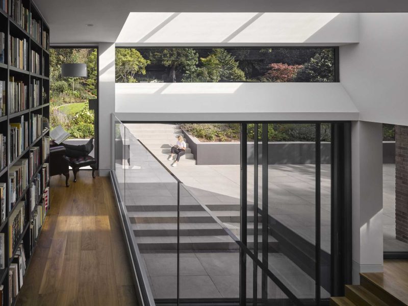 A 1920s British home received a modern rear addition with a sunken living room and mezzanine reading level.