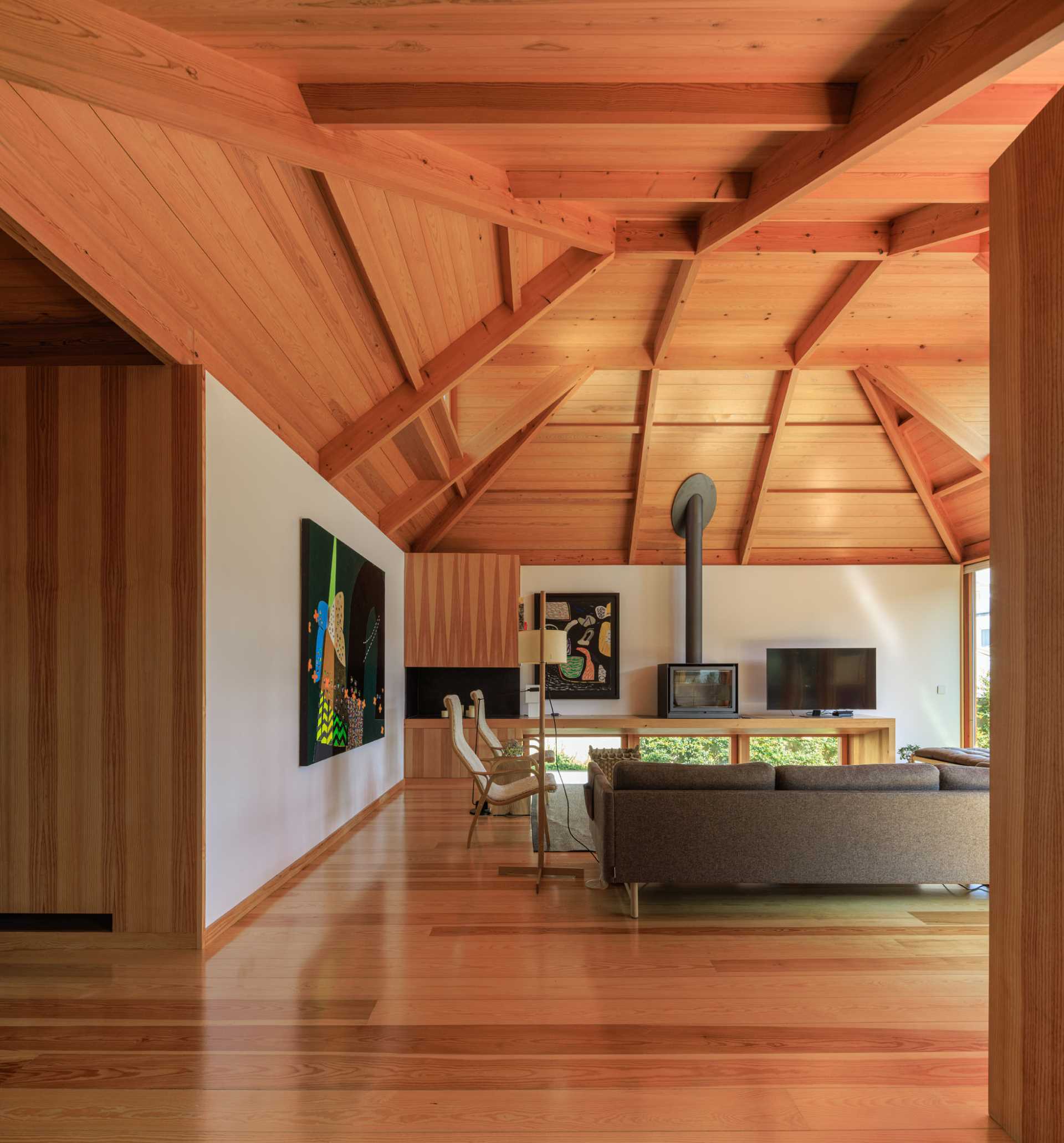 A modern living room with an angular wood ceiling.