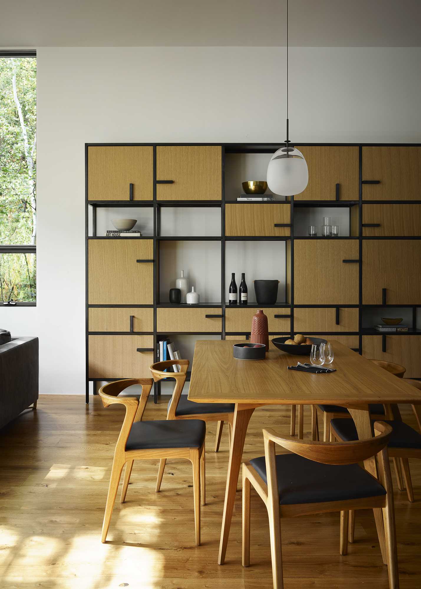 A modern open-plan dining area with white oak cabinets and black accents.