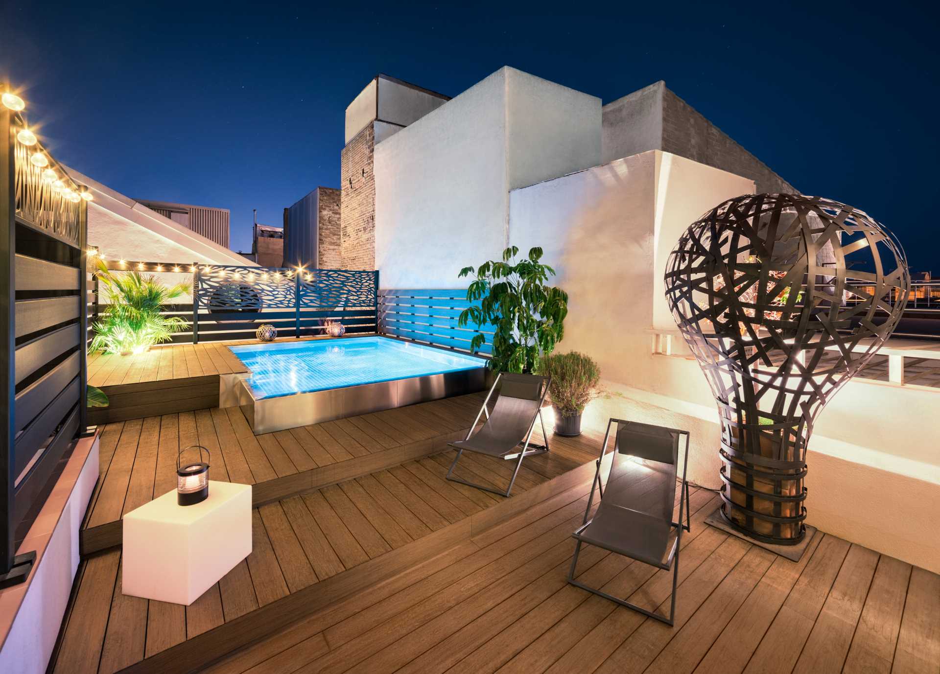This rooftop includes a deck with an overflowing stainless steel pool and seating areas.