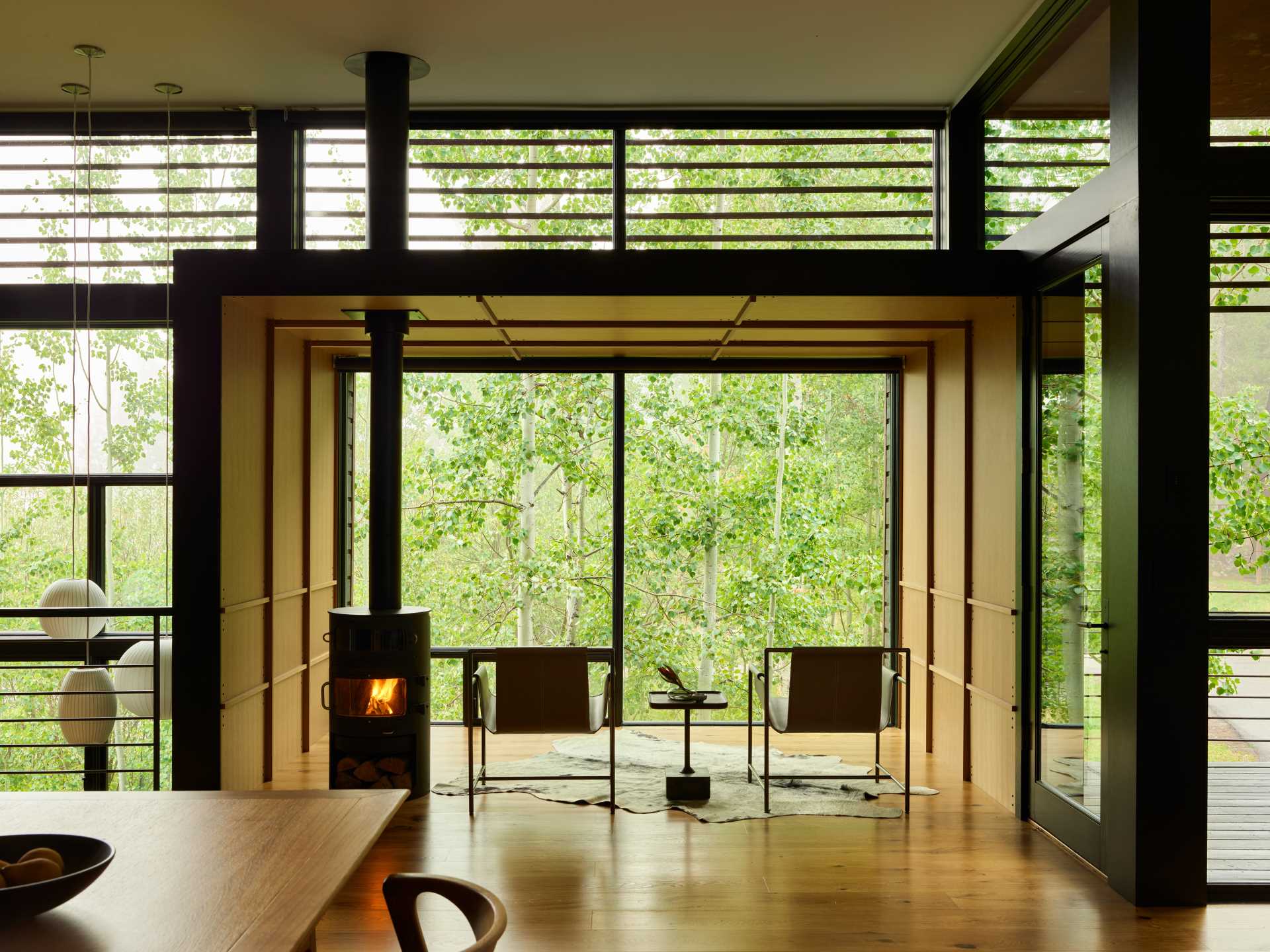 The protruding wood box has been furnished with a simple fireplace and a pair of chairs facing the tree view.