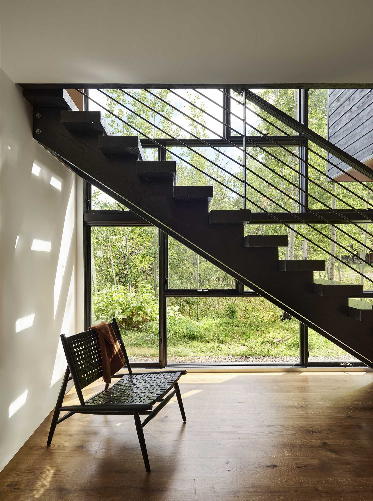 Stairs by the two-story window lead from the upper level of the home down to the guest room.