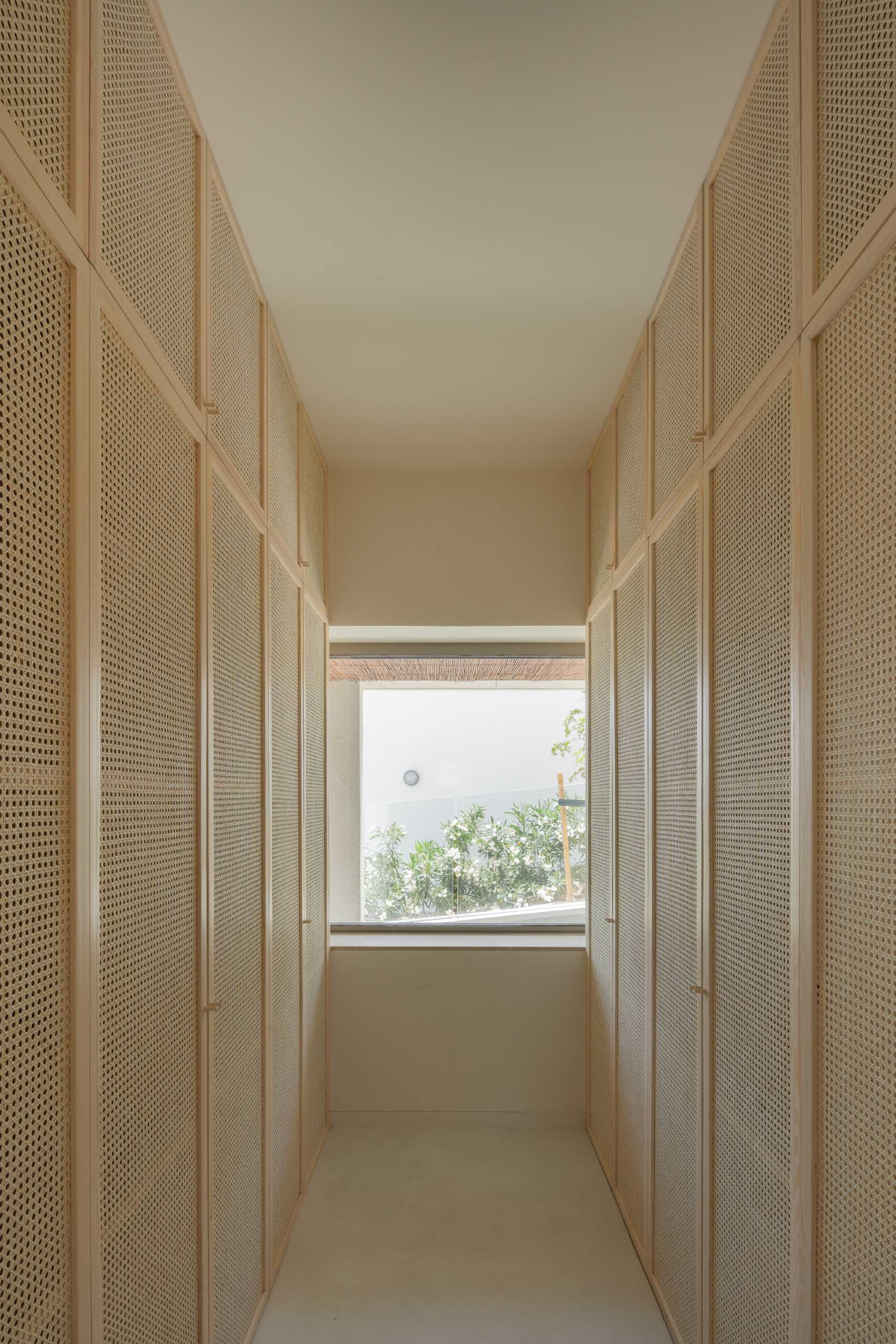 A walk-in closet with artisanal rattan and light pine wood carpentry.