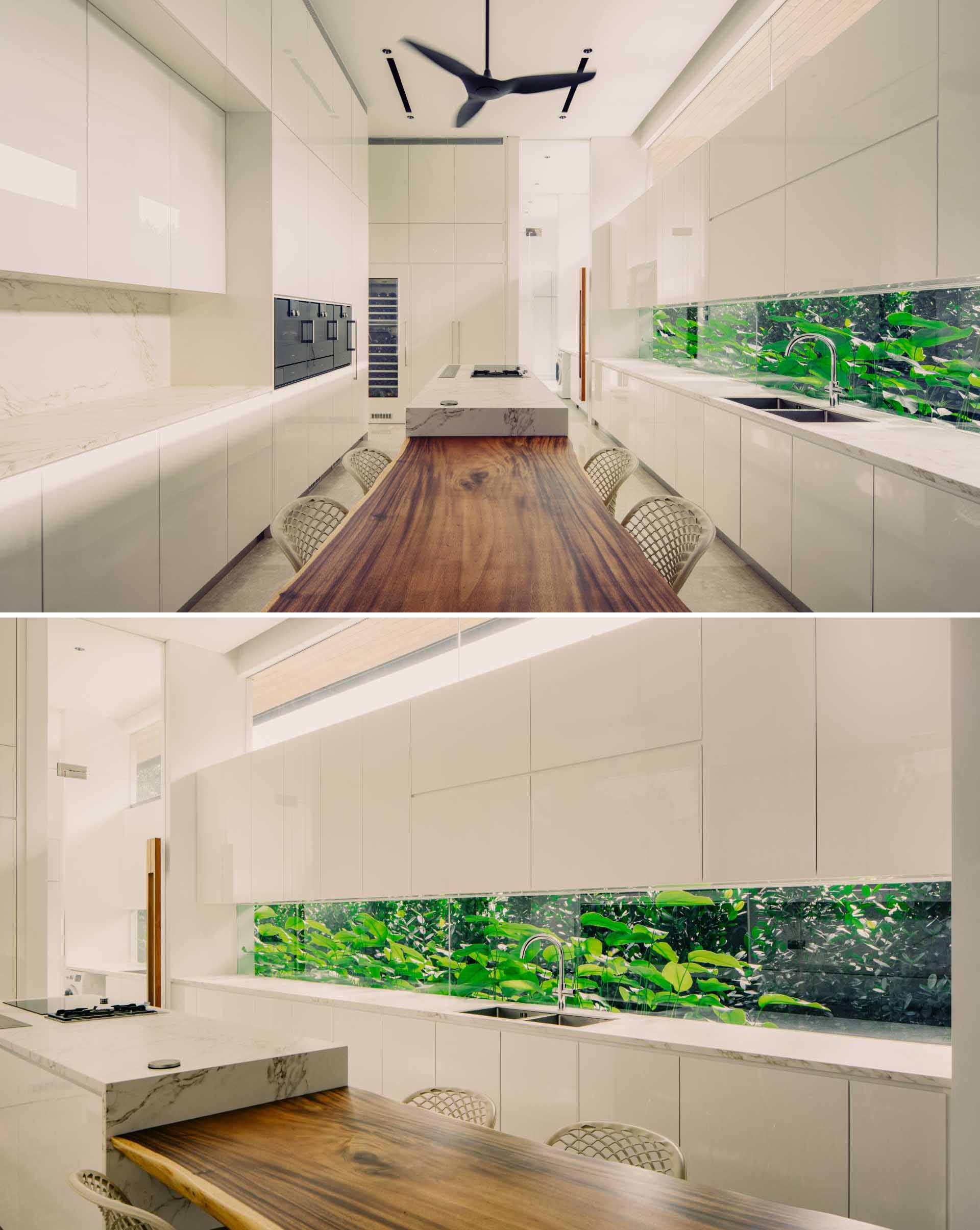 In this modern kitchen, white cabinets allow the plants seen through the long horizontal window to be the focal point.