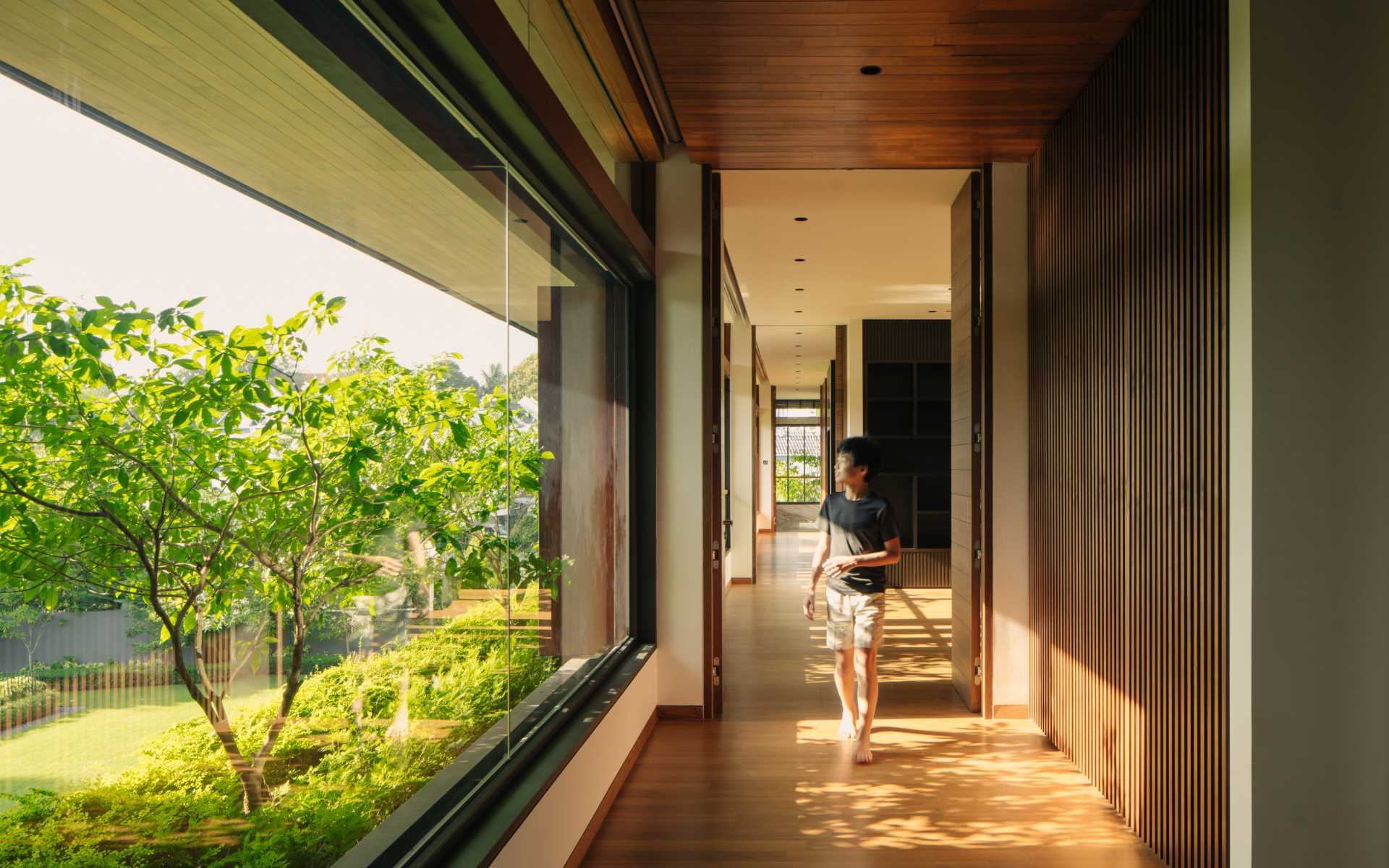 A modern home with glass-lined hallways and wood floors.