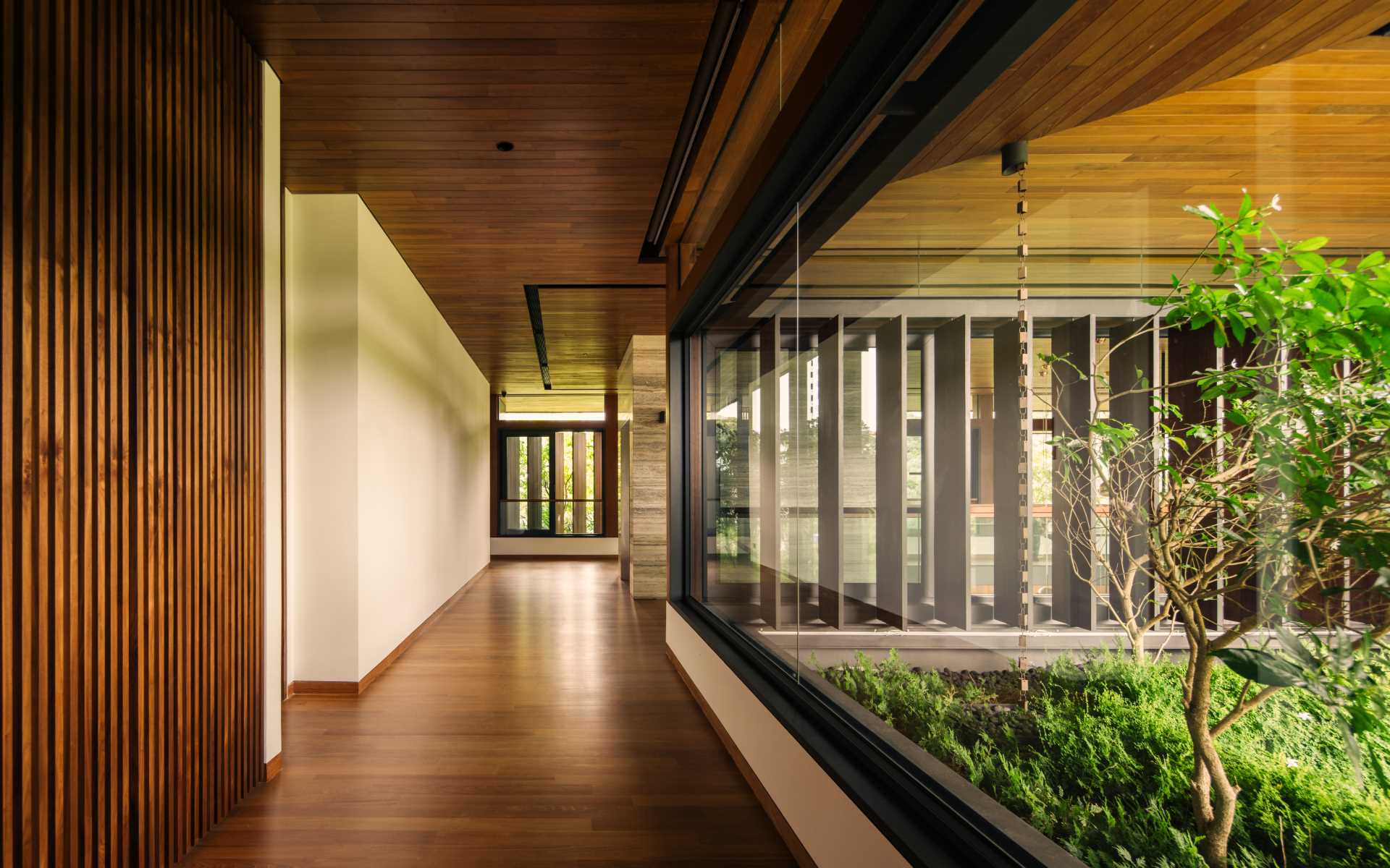 A modern home with glass-lined hallways and wood floors.