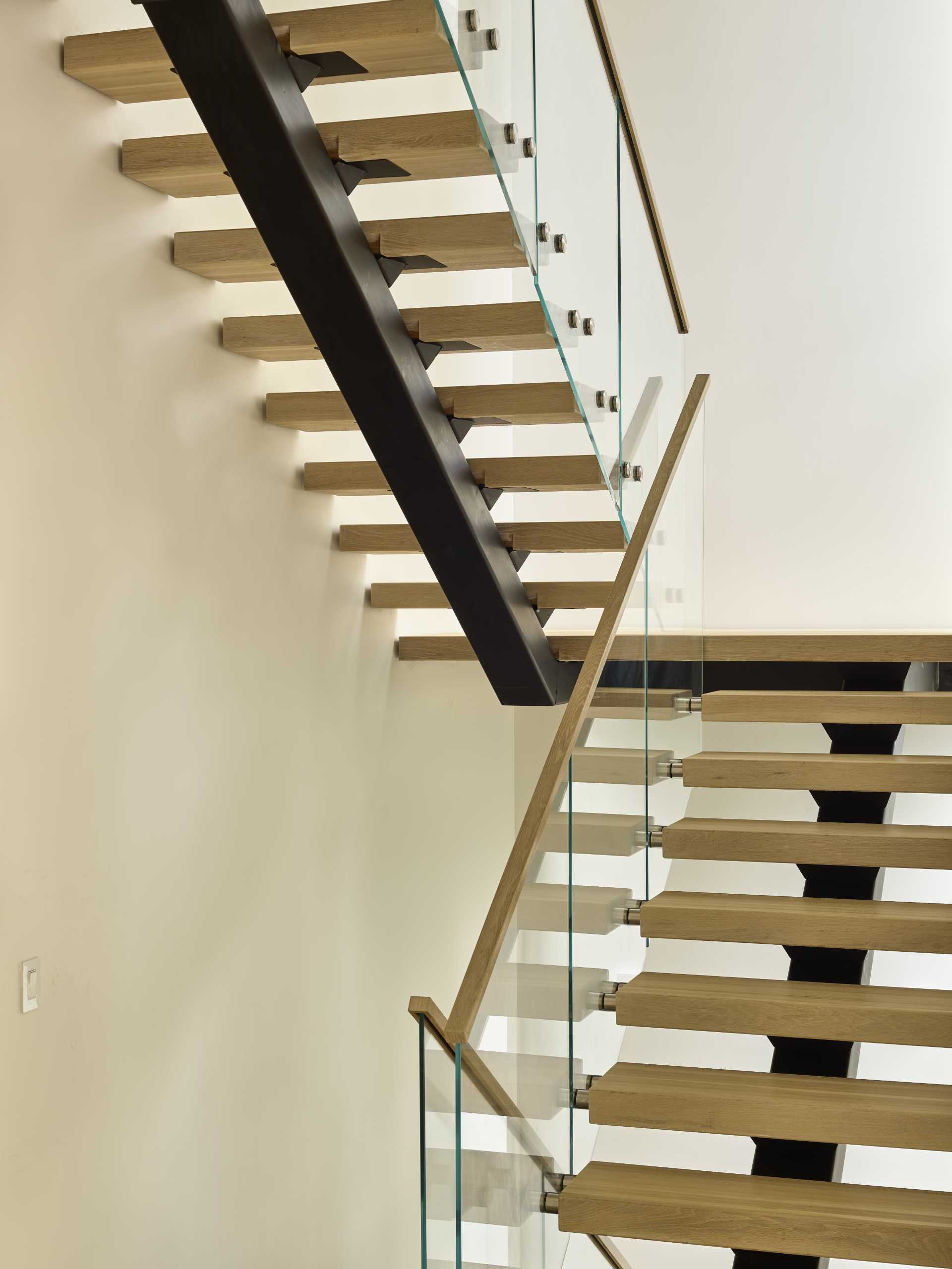 Wood and steel stairs with glass railings connect the various floors of this modern home.