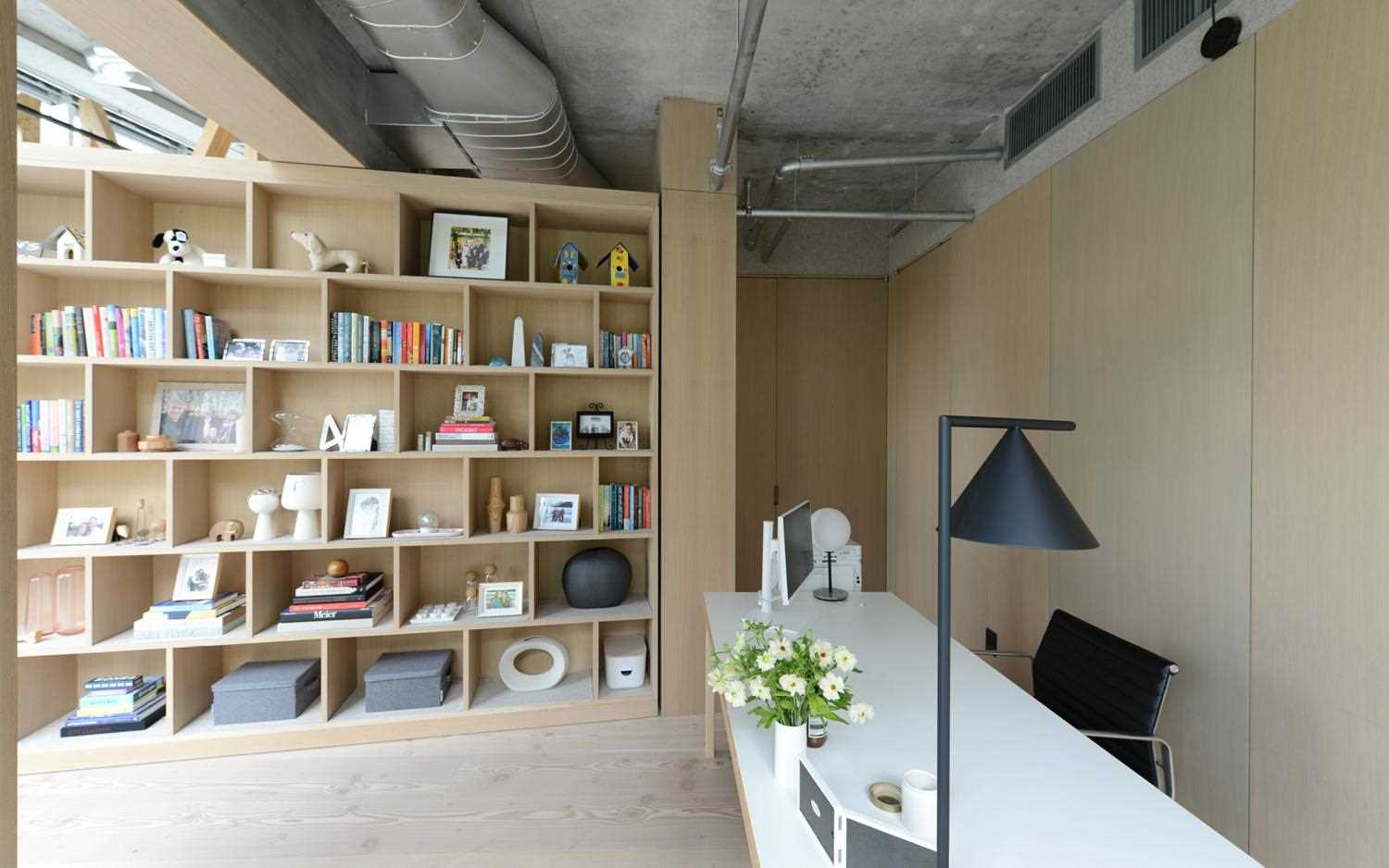 A home office is hidden from the living room behind an oversized pivoting bookshelf.