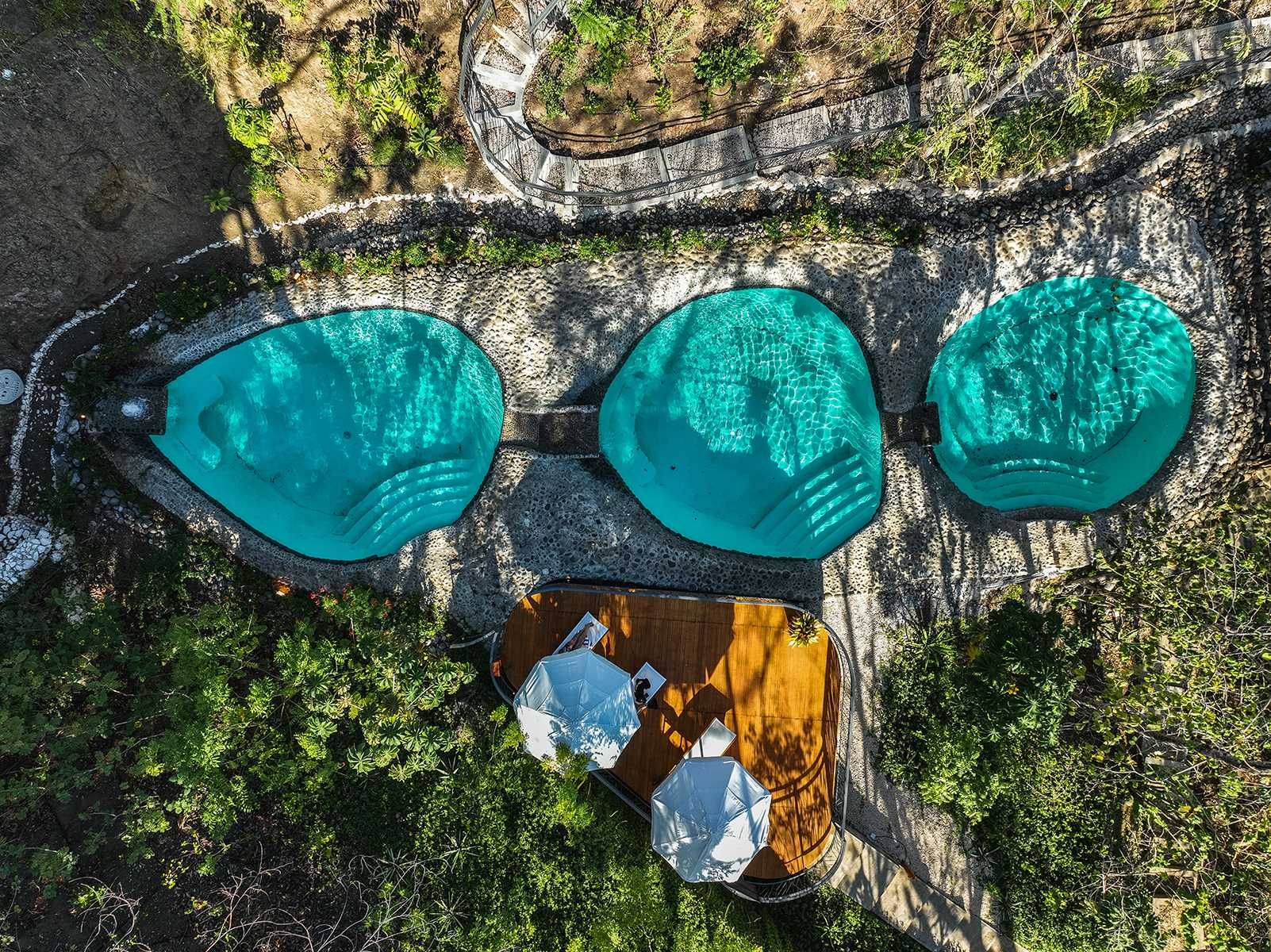 These swimming pools each have a round shape and are tiered allowing the water to flow between them.