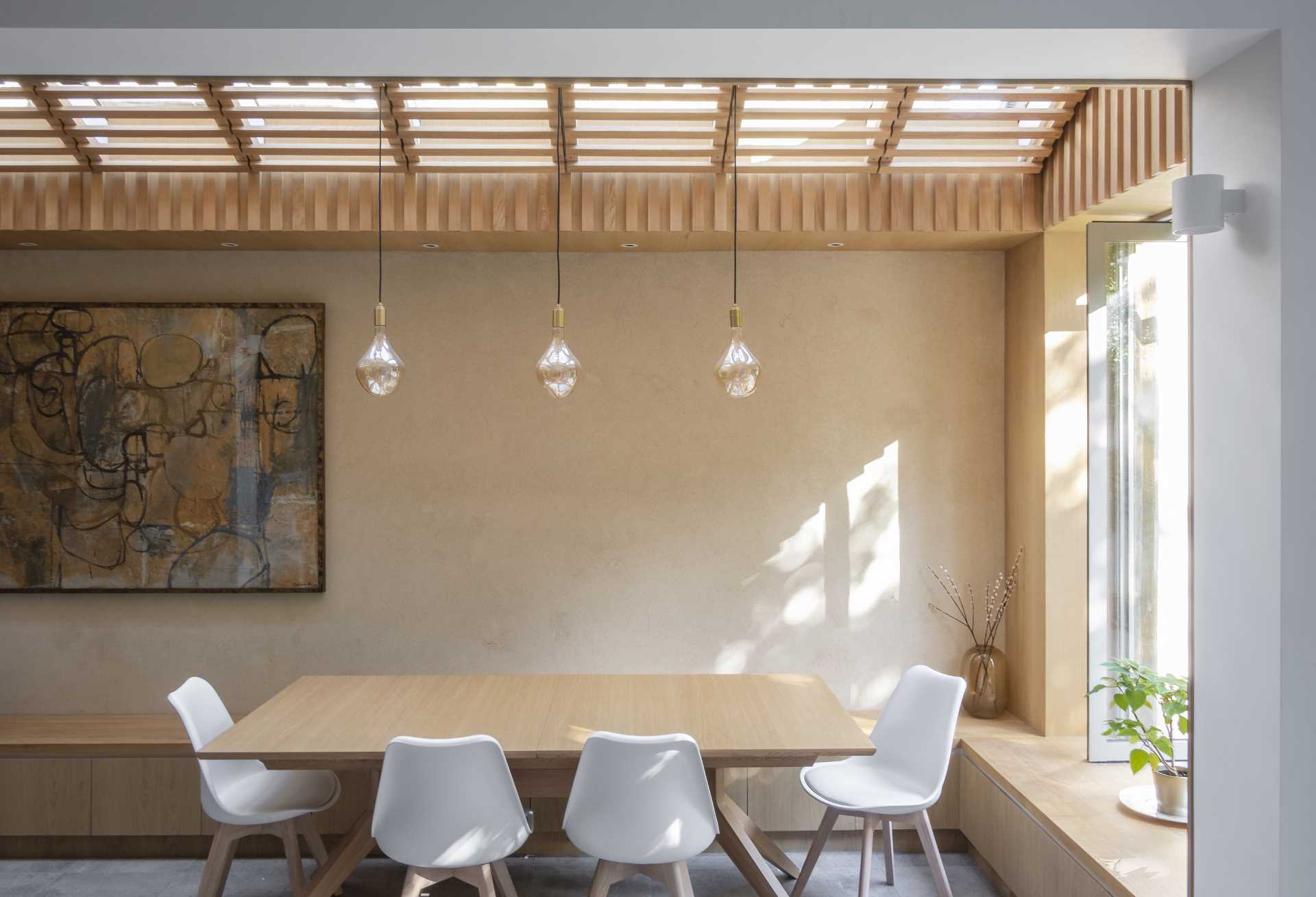 To avoid this modern dining room being overlooked by the neighbors' upper windows, the architects designed a series of louvres made of oak to line the underside of the roof.