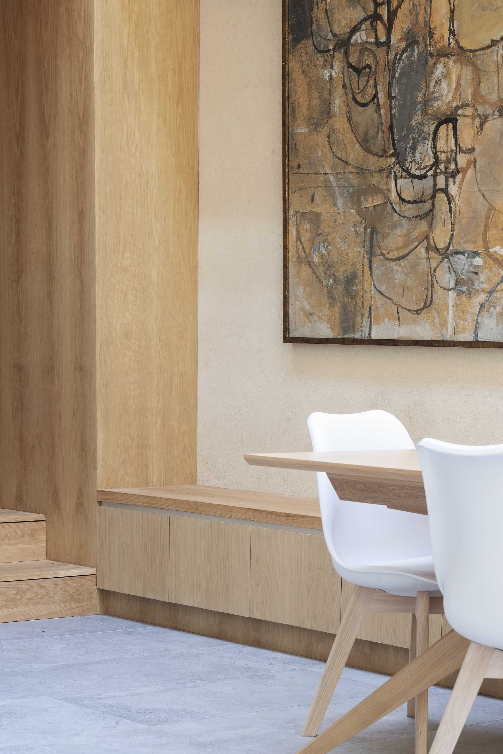 A modern dining area with built-in wood storage that lines the wall.