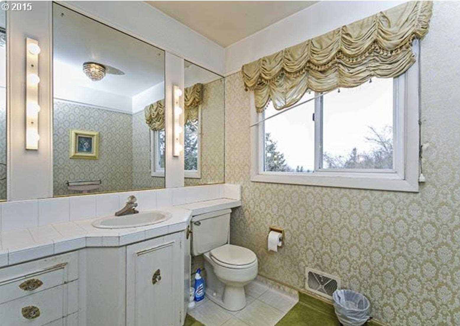 Before - a dated mid-century modern bathroom includes wallpapered walls and a tiled vanity countertop.