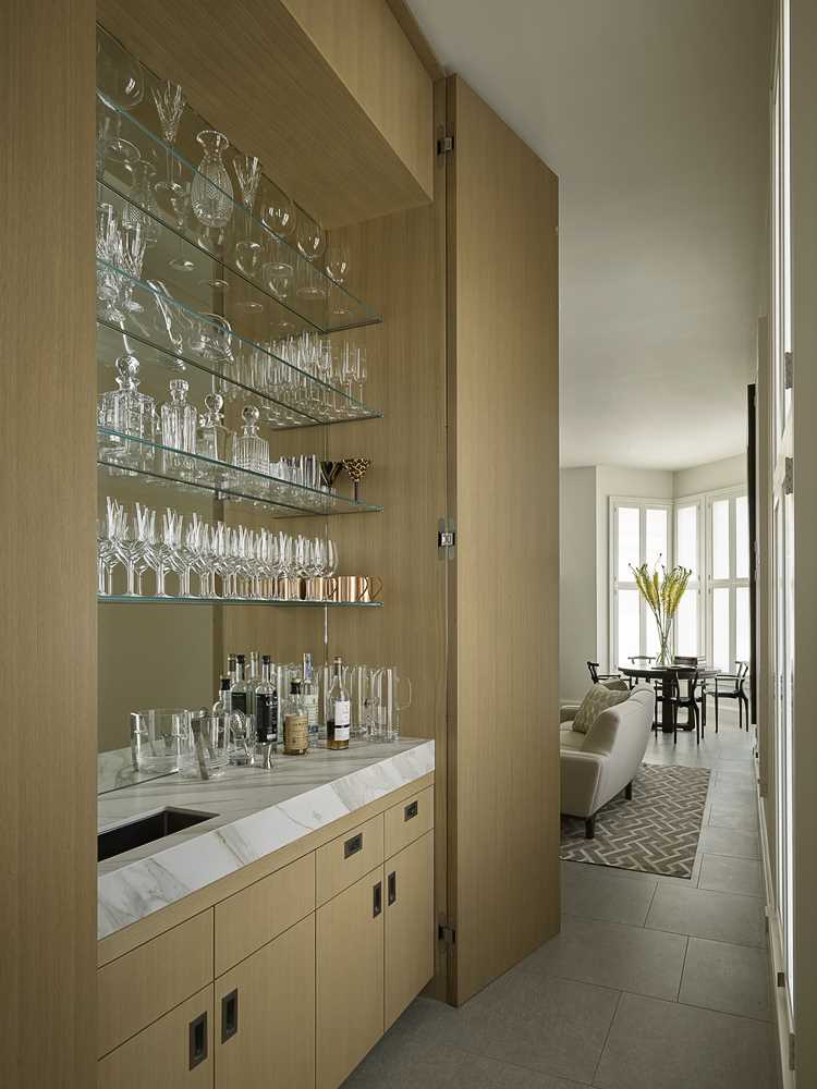 A custom cabinet that hides a wet bar with a mirror back and glass shelves.