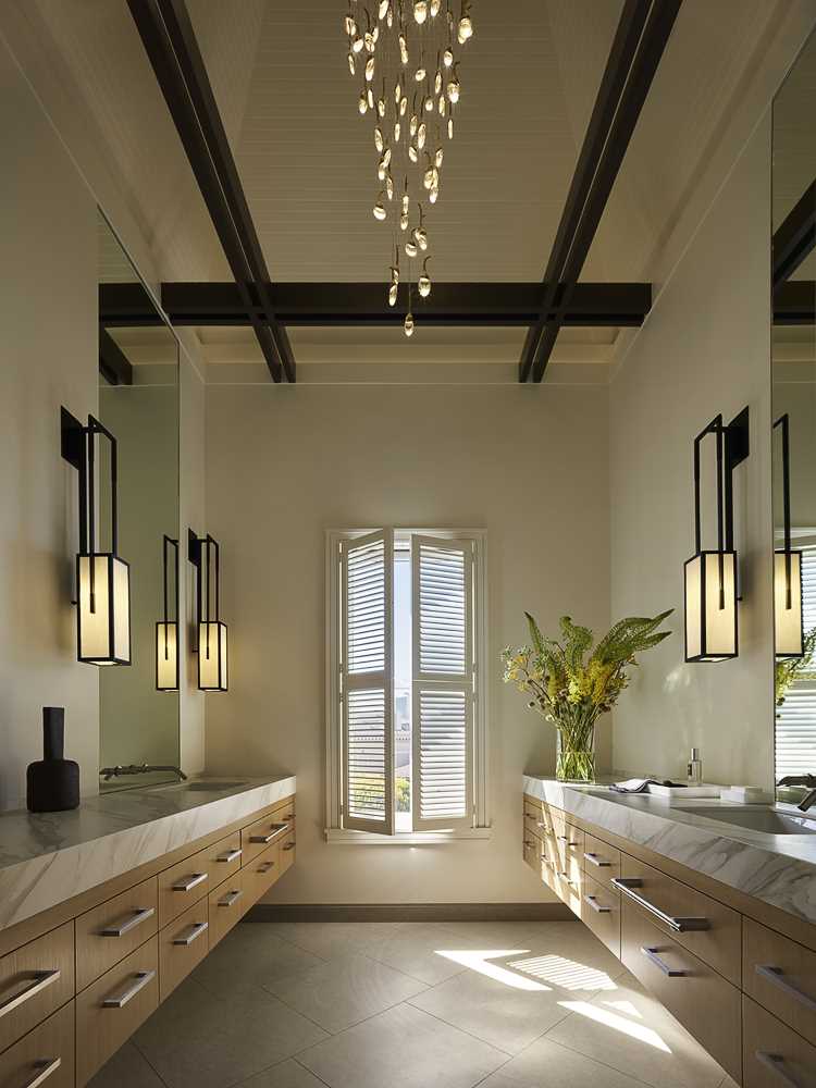 The design team placed this primary bath in the turret of the home, with modern light fixtures creating a dramatic interplay between the new and old elements of the residence.