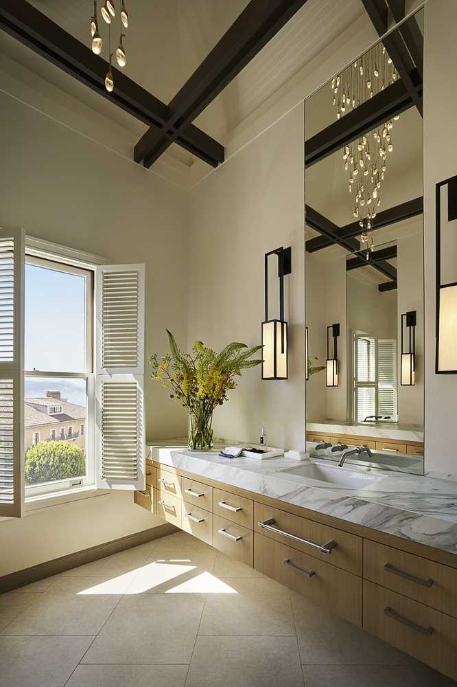 The design team placed this primary bath in the turret of the home, with modern light fixtures creating a dramatic interplay between the new and old elements of the residence.