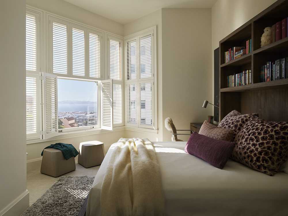 In this bedroom, there's a dark wood bed frame and headboard that contrast the light walls, while the view becomes the focal point.