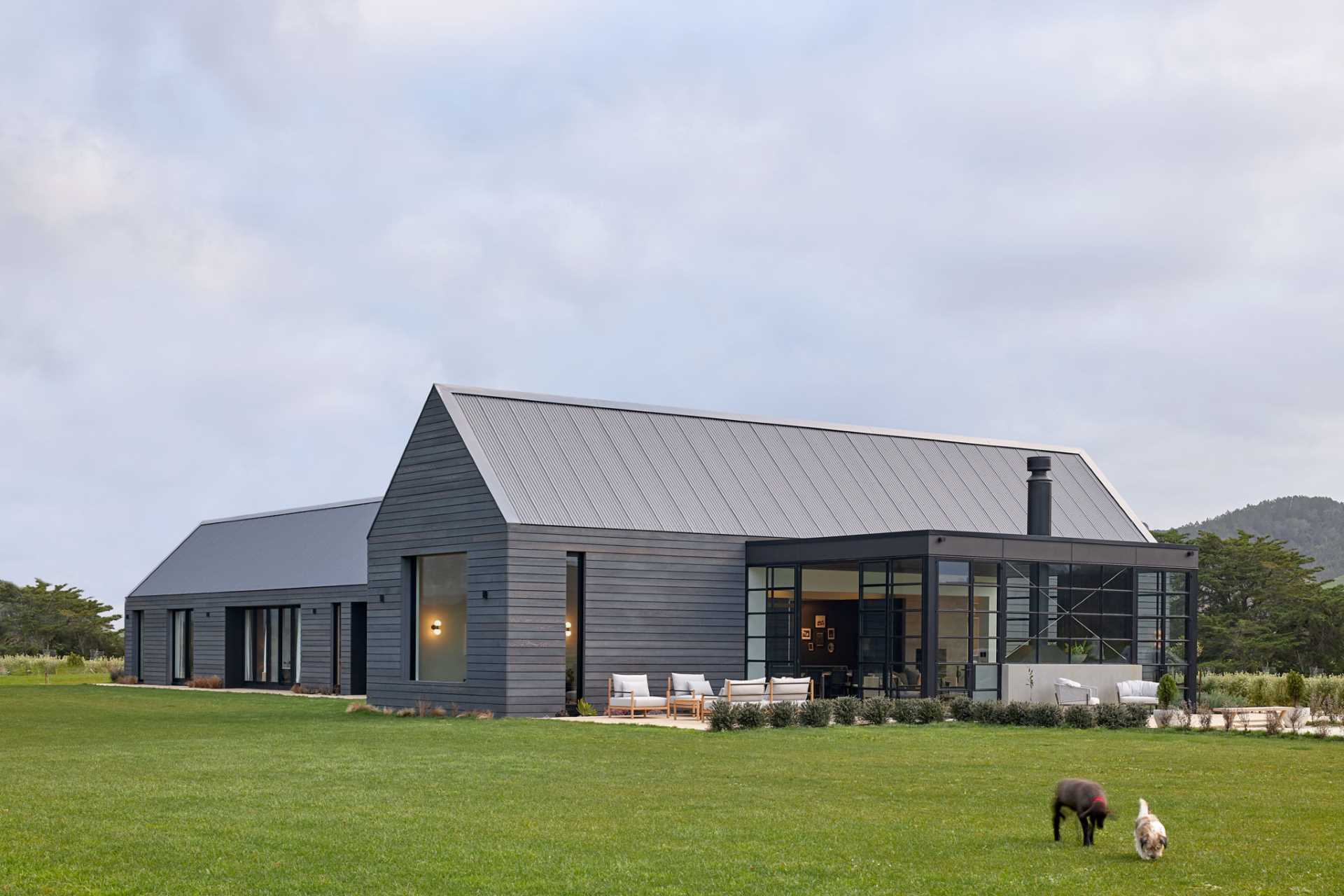 A contemporary farmhouse with grey-stained weathered wood siding and a standing seam grey metal roof.
