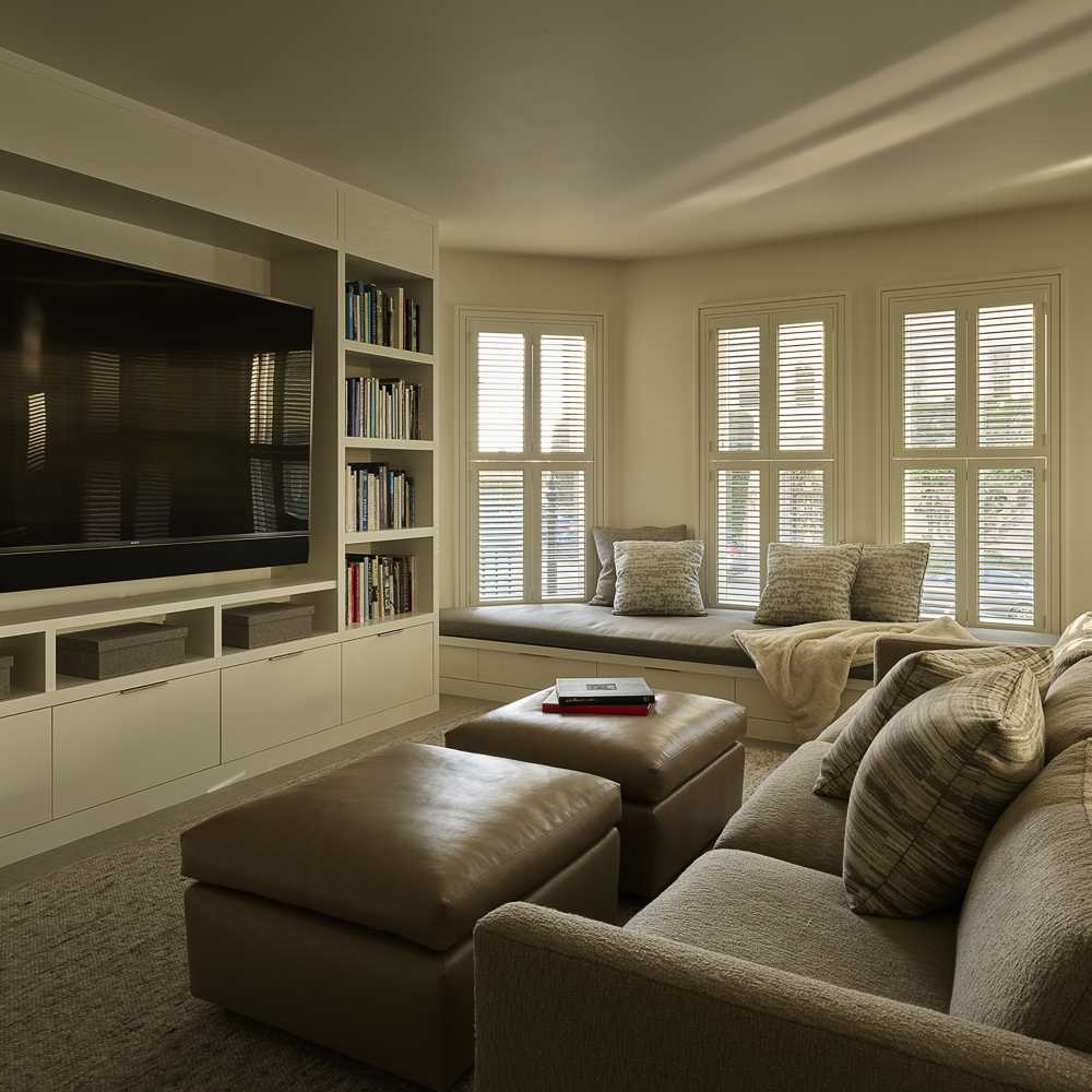 A contemporary living room with built-in shelving and cabinetry surrounding the TV.