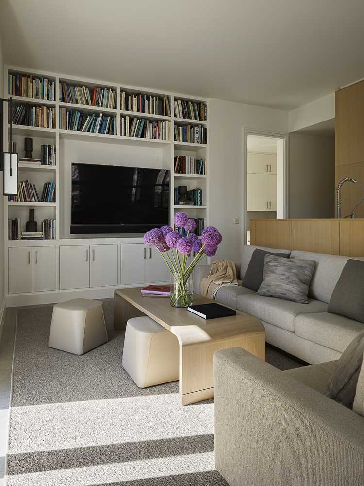 A contemporary living room with built-in shelving and cabinetry surrounding the TV.