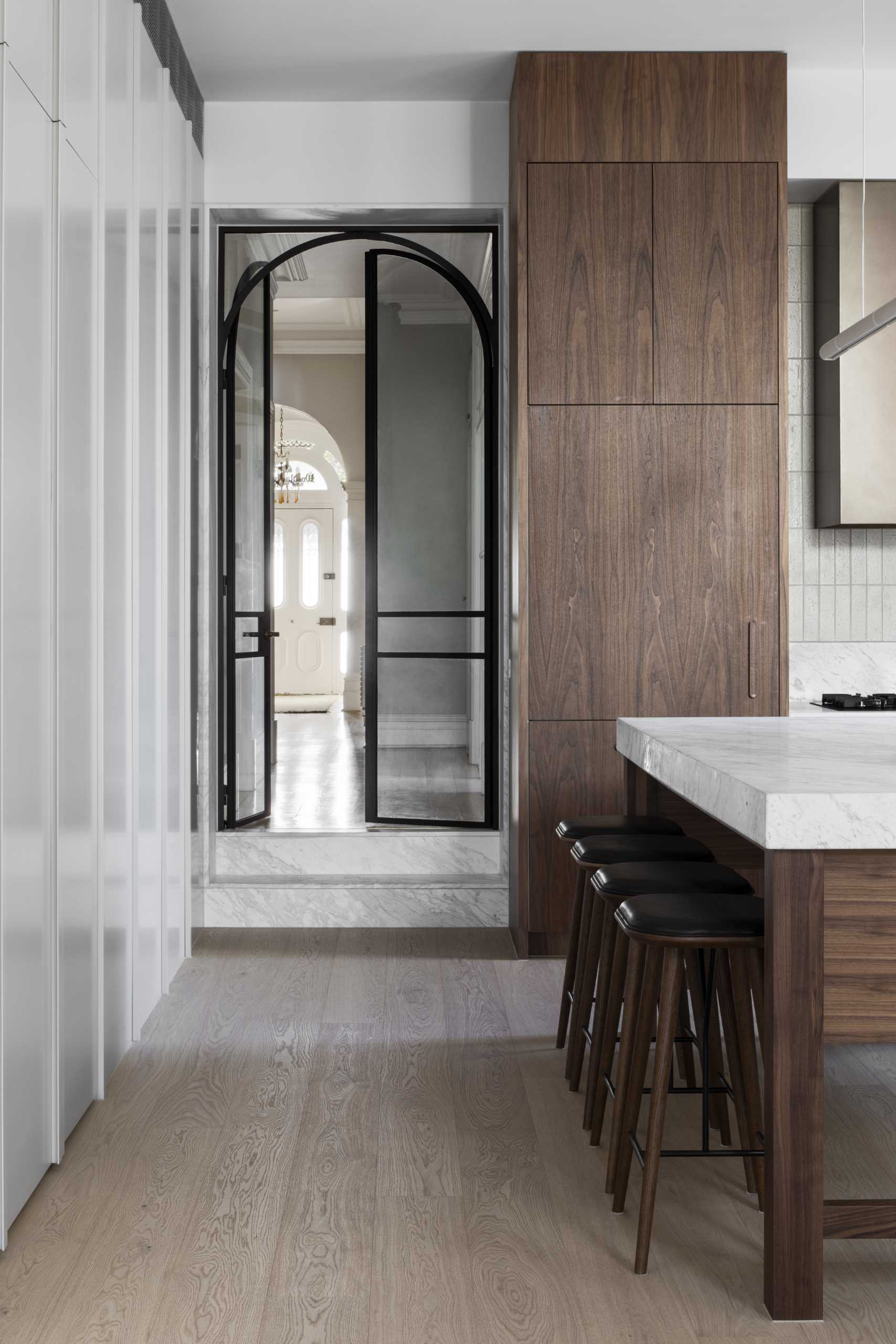A black-framed arched door connects the original parts of the home with the new addition.