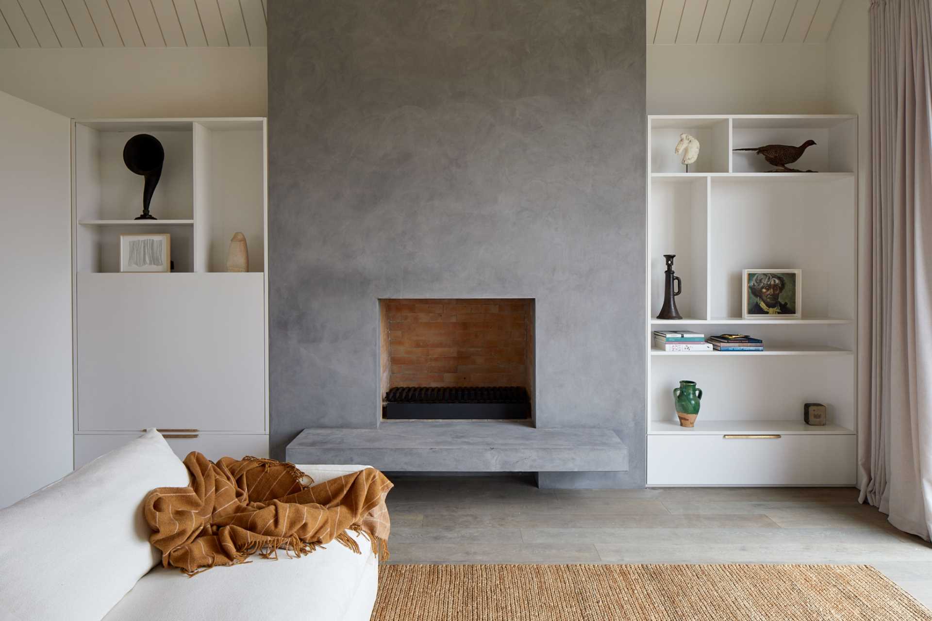 A modern living room with built-in shelving and cabinets that flank either side of the fireplace.