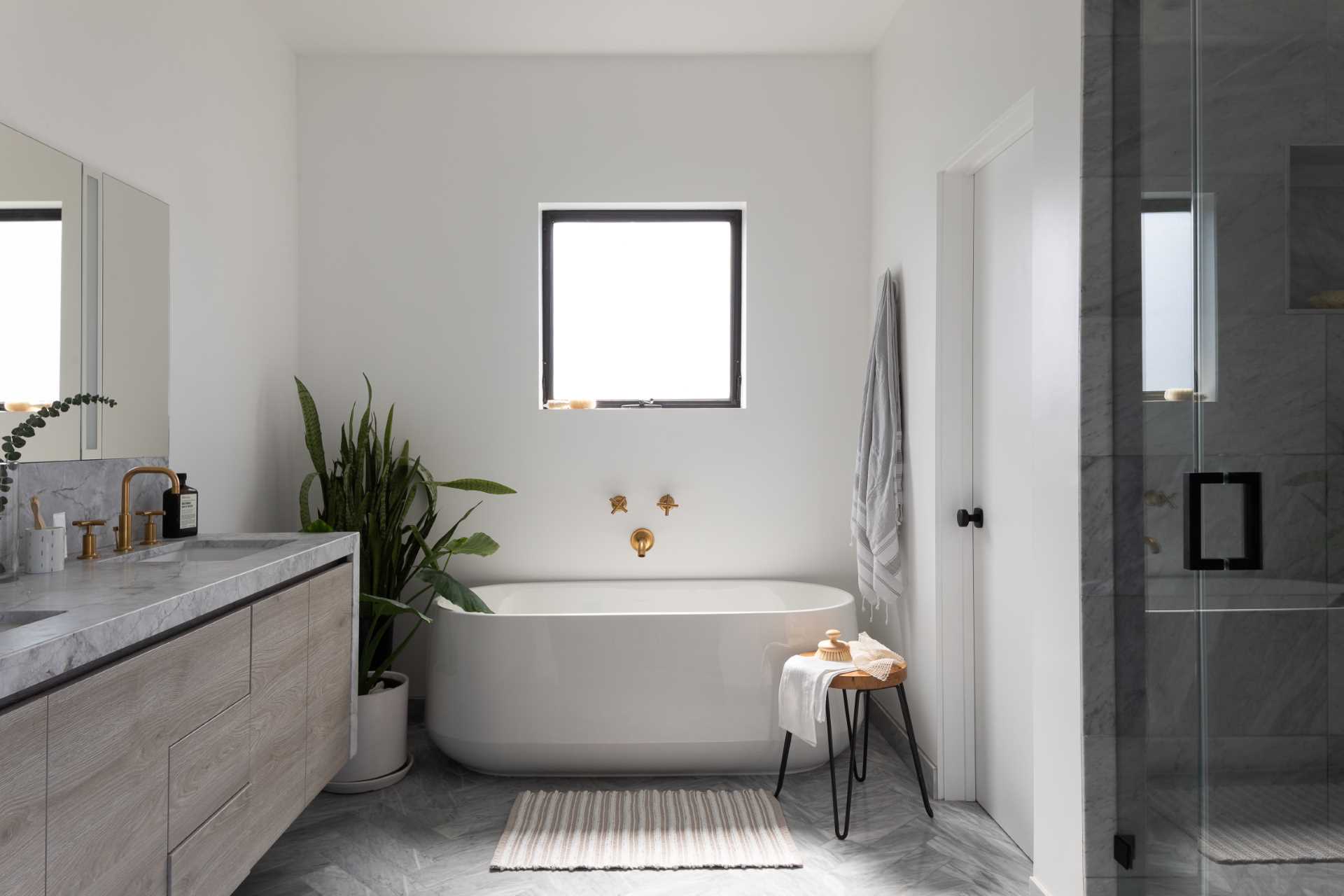 This modern en-suite bathroom includes a freestanding bathtub, a double vanity, and glass-enclosed walk-in shower.