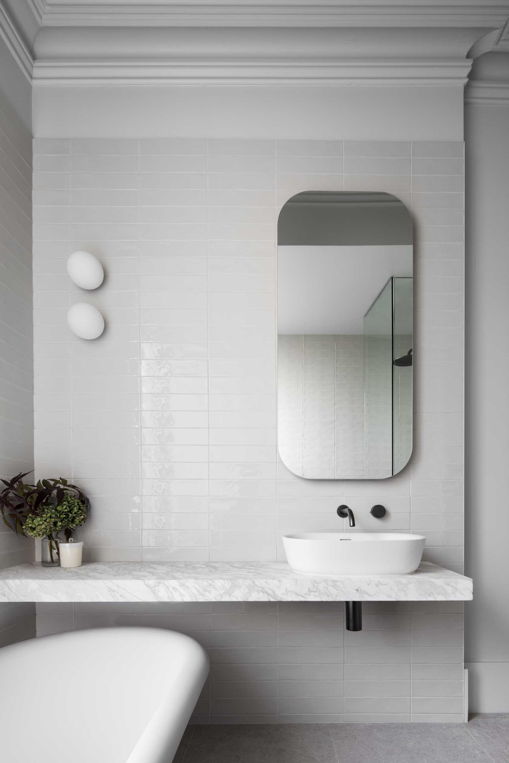 In this bathroom, there's a floating vanity and freestanding bathtub, while an opaque window provides privacy and at the same time, allows the light to filter through.