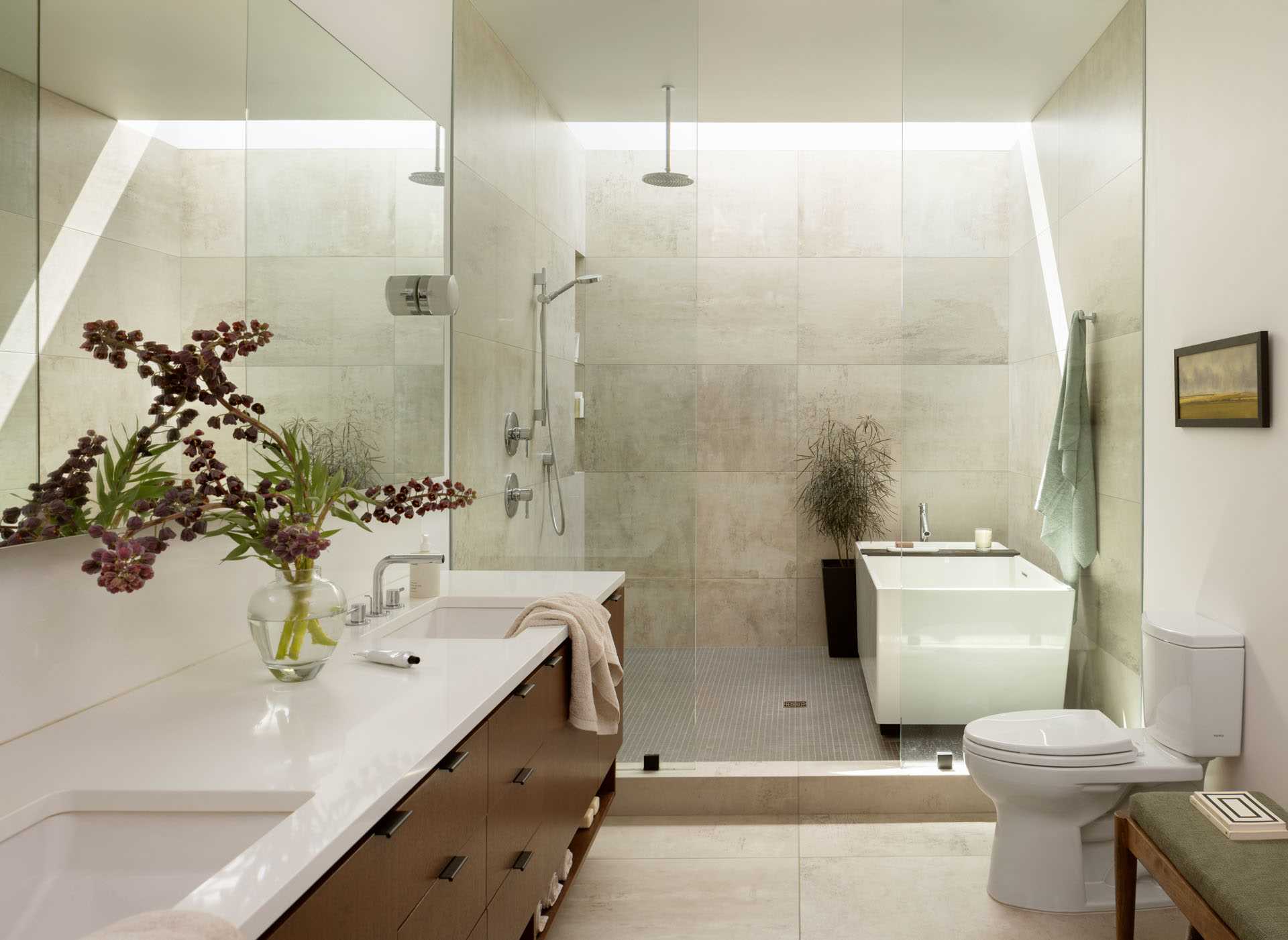 A modern bathroom with a wide skylight in the wet room and a strategically placed mirror that makes the room feel larger.