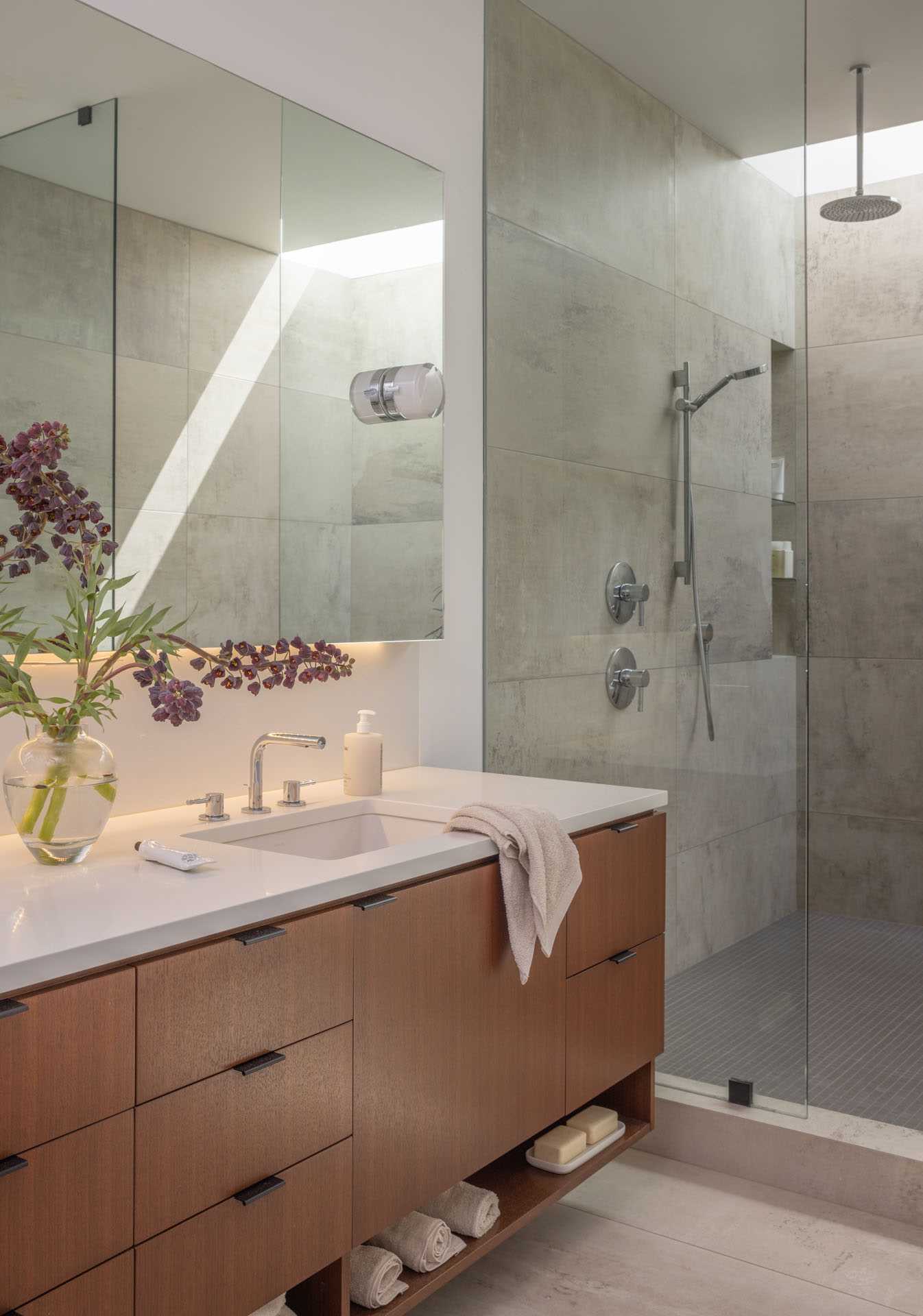 A modern bathroom with a wide skylight in the wet room and a strategically placed mirror that makes the room feel larger.