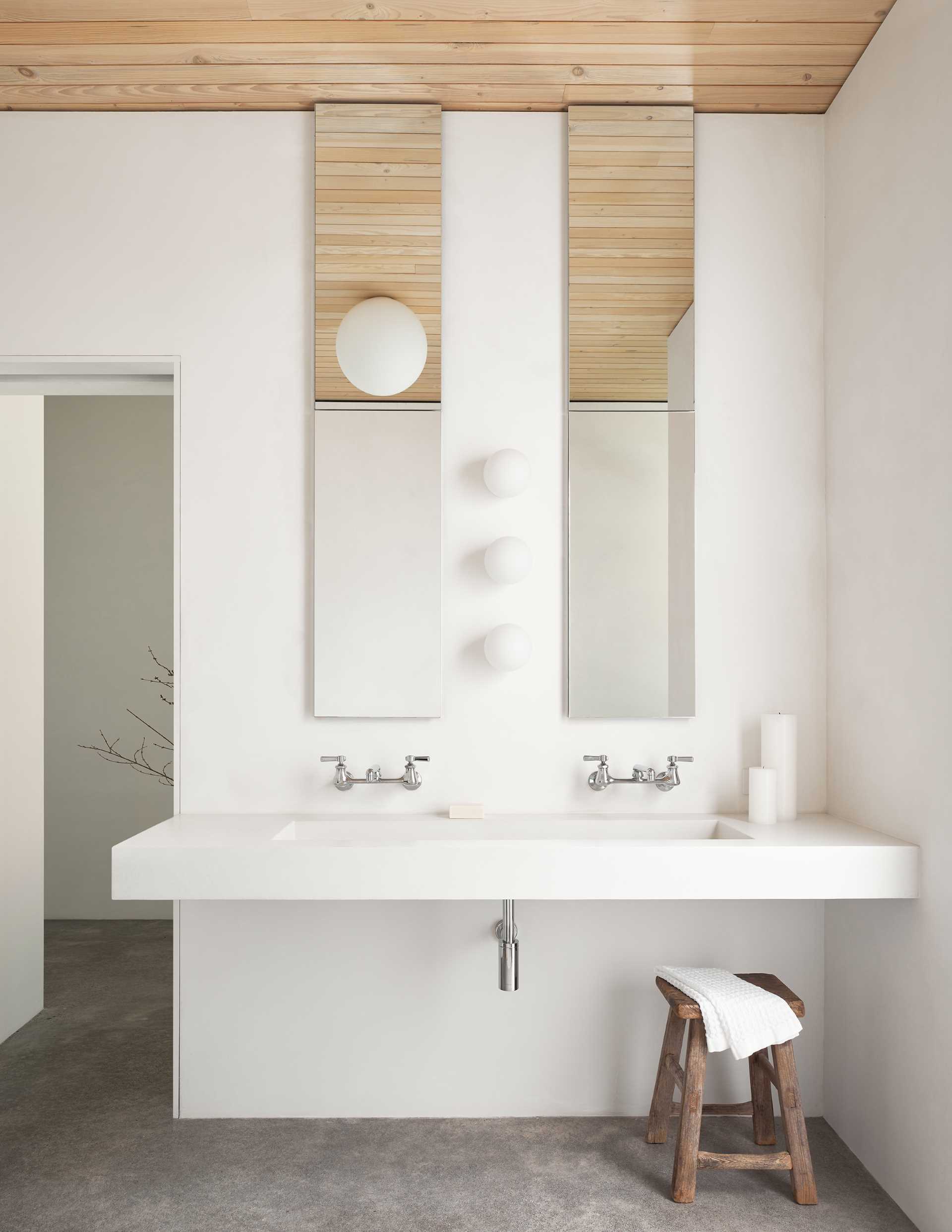 A modern bathroom with a floating custom concrete sink and tall mirrors.