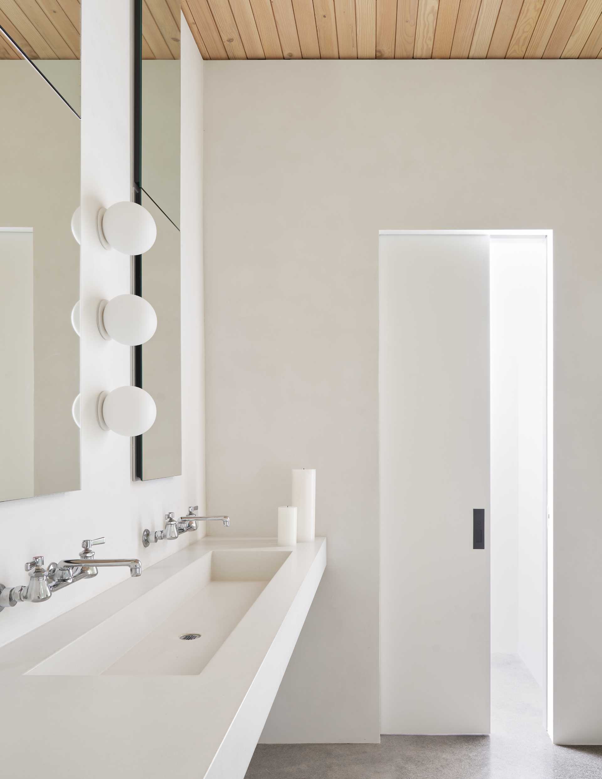 A modern bathroom with a floating custom concrete sink and tall mirrors.