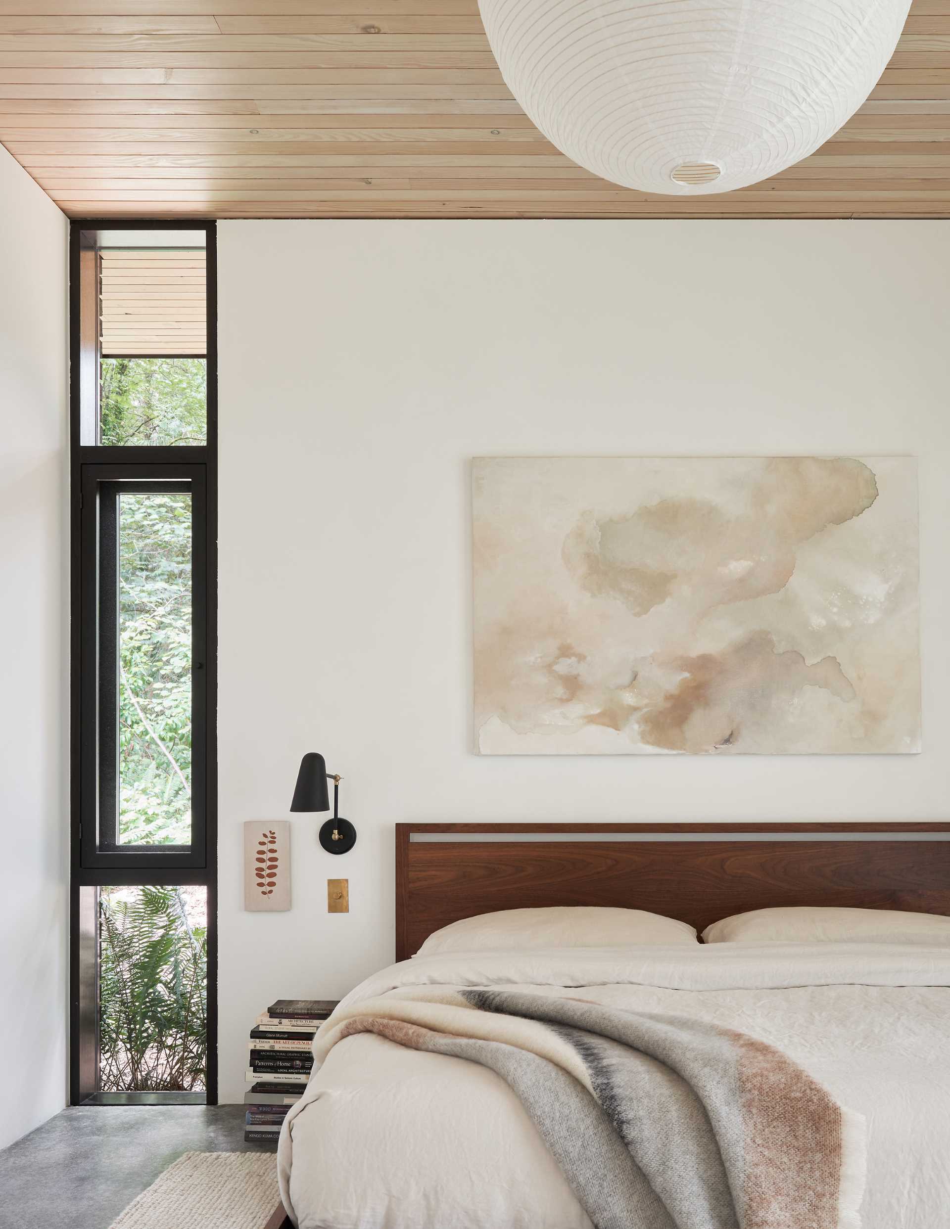 This modern bedroom features a custom bed designed by the architects and built by Joel Kikuchi, while an ivory woven wool rug softens the polished concrete floor.