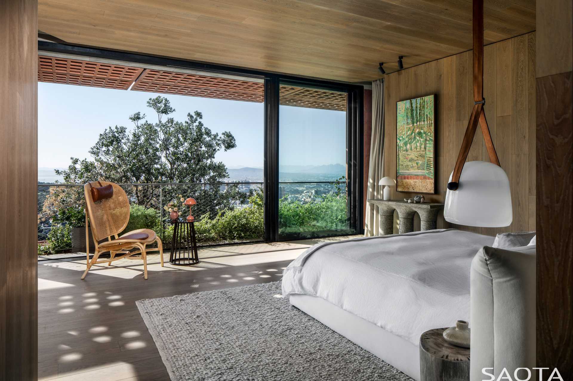 In this modern bedroom, sliding glass doors open the bedroom to the outdoors, while wood adds a sense of warmth to the room.