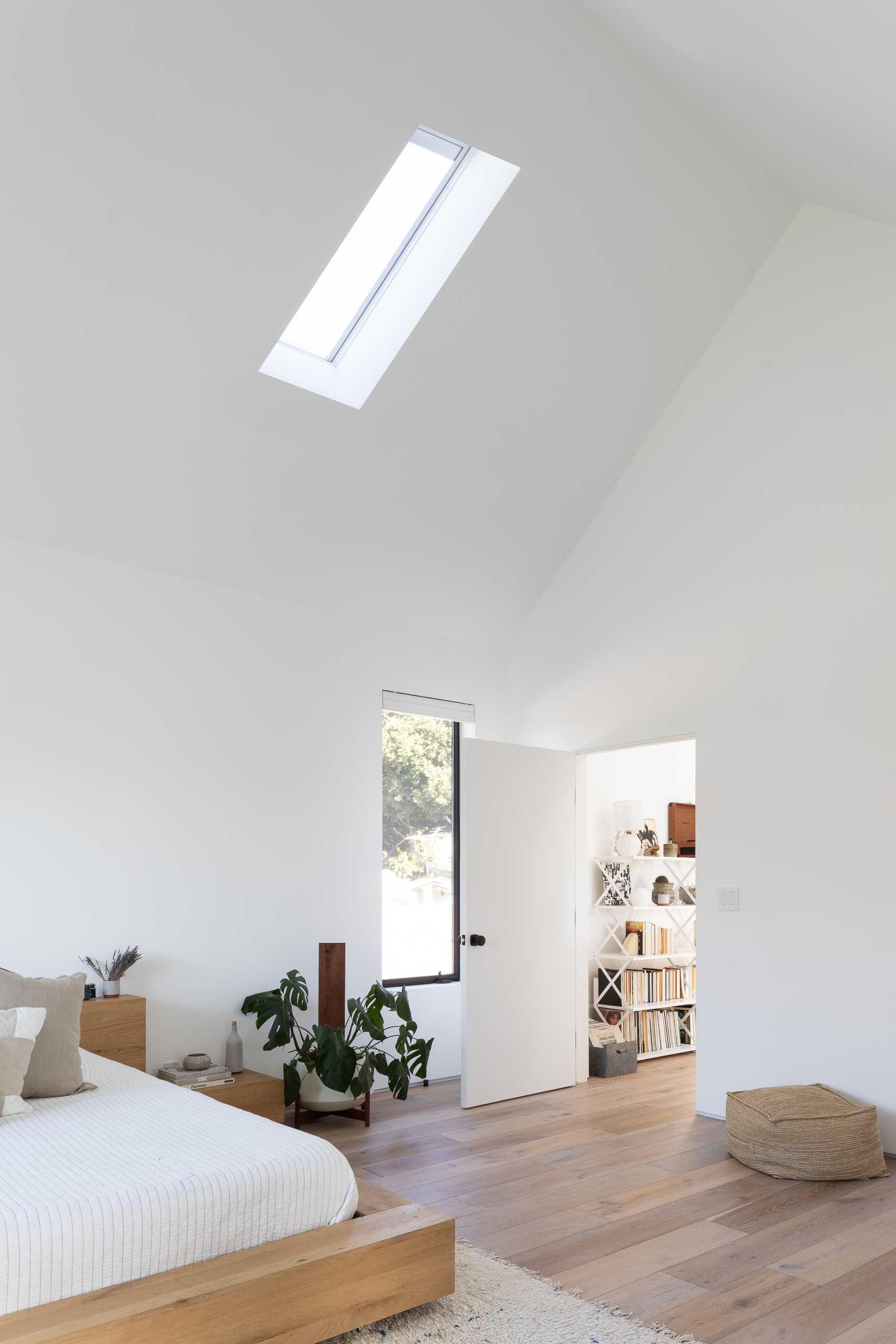 In this modern primary bedroom, the vaulted ceiling makes the room feel large, while a window seat creates a cozy place to relax.