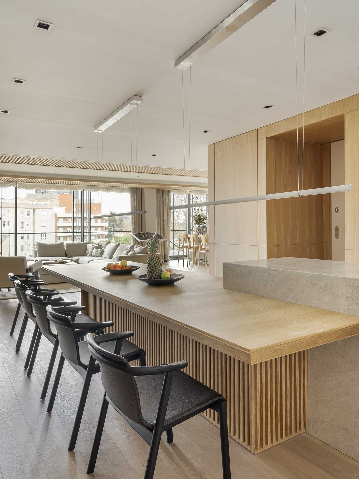 An open and spacious kitchen layout has been designed to invite engagement, where a marble bar and a long wooden dining table play host. A mirrored wall has also been included in this space.