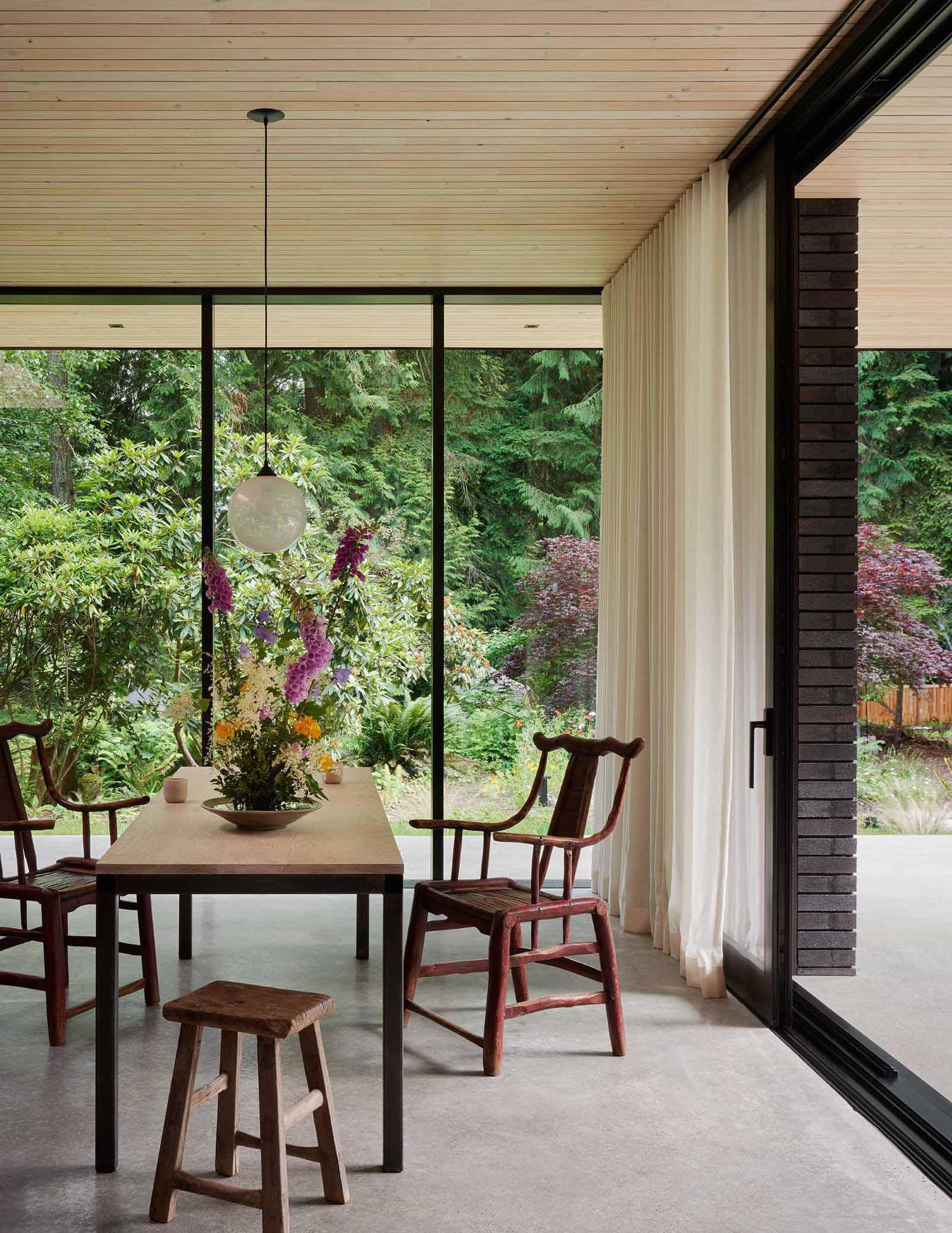 This modern home has a Douglas fir wood ceiling that's been lye-washed, while in the dining area, a table made from oak and steel has been designed by ?GO'C.