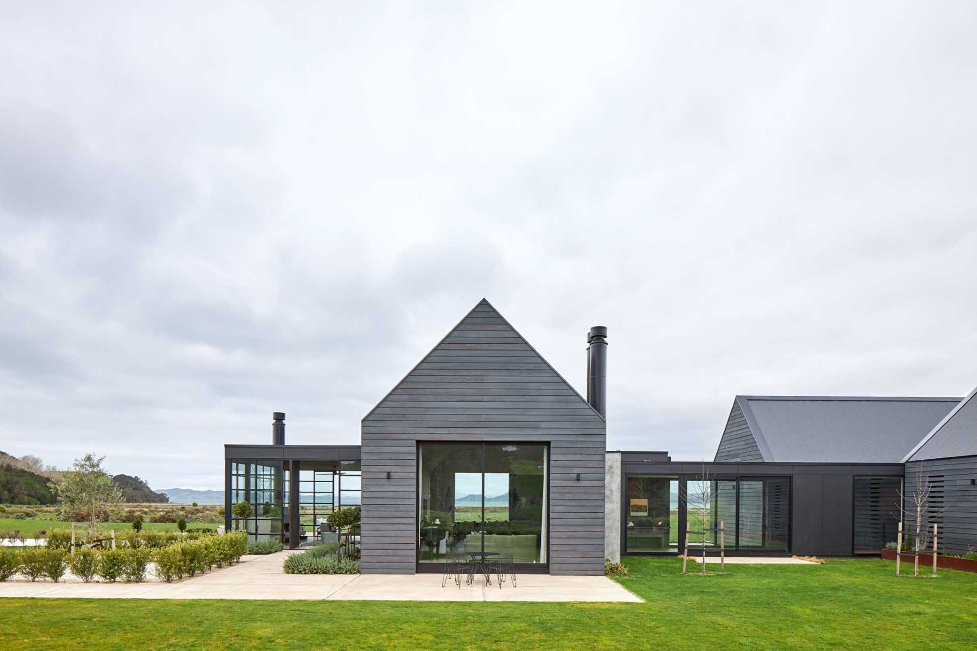 A contemporary farmhouse with grey-stained weathered wood siding and a standing seam grey metal roof.