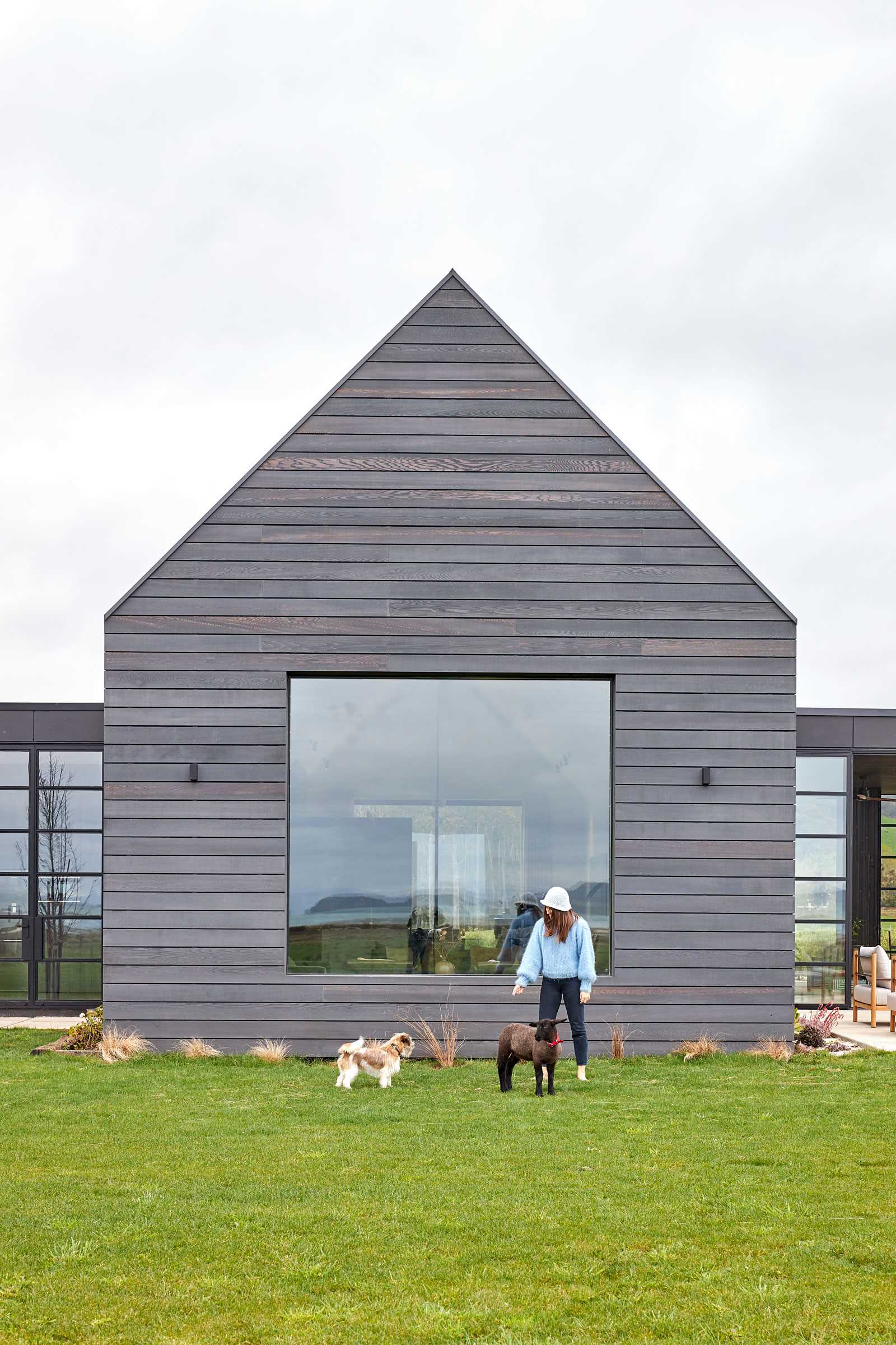 A contemporary farmhouse with grey-stained weathered wood siding and a standing seam grey metal roof.