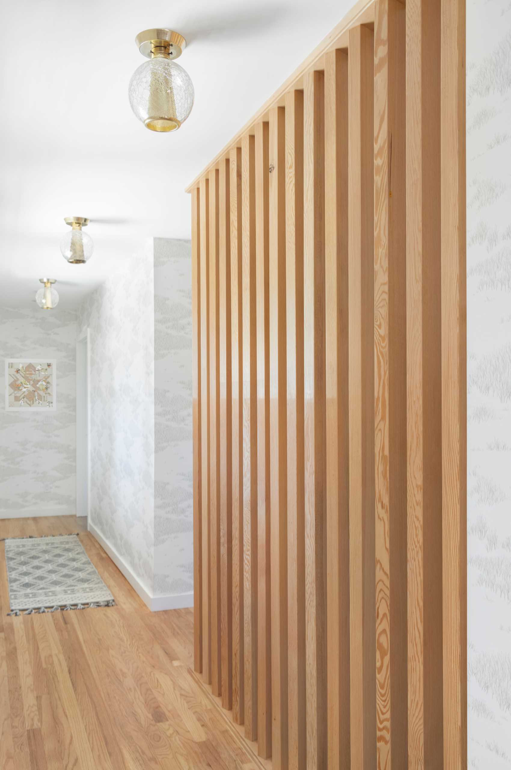 This updated hallway includes vertical wood slats that serve as dividers not only to the downstairs stairwell but also in the family room itself.