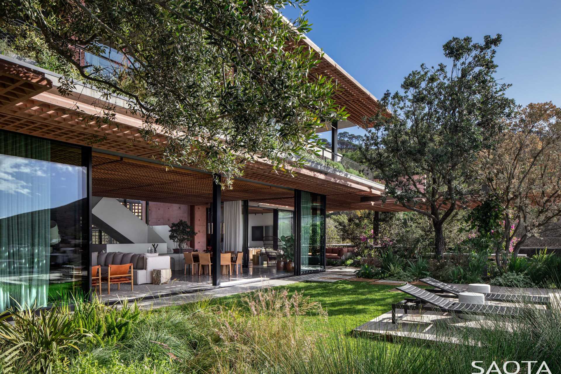 This modern home features a swimming pool and outdoor spaces, some of which are paved in Rustenburg granite and local sandstone.