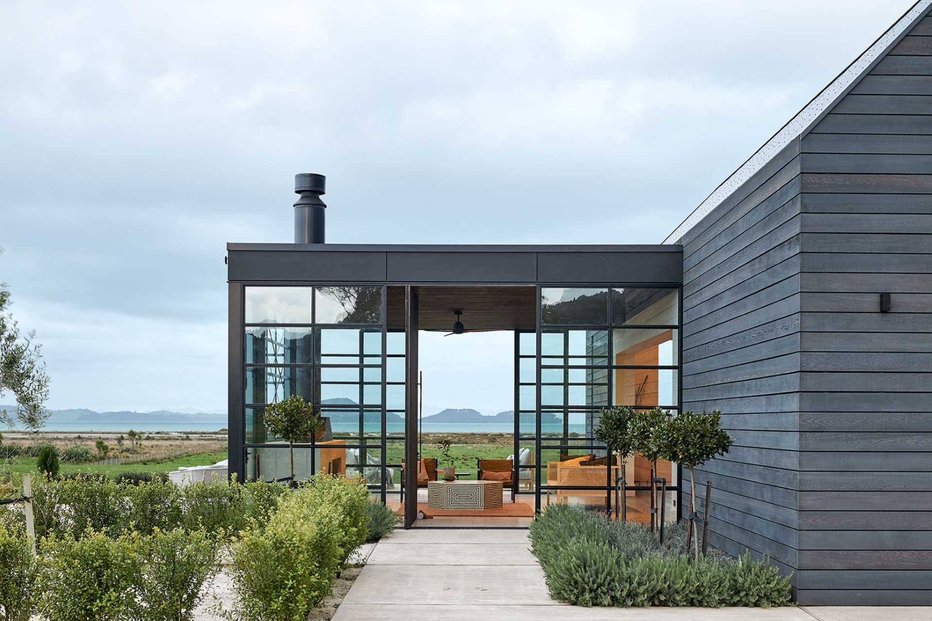 A modern farmhouse has a room with glass walls that includes a fireplace and living room.