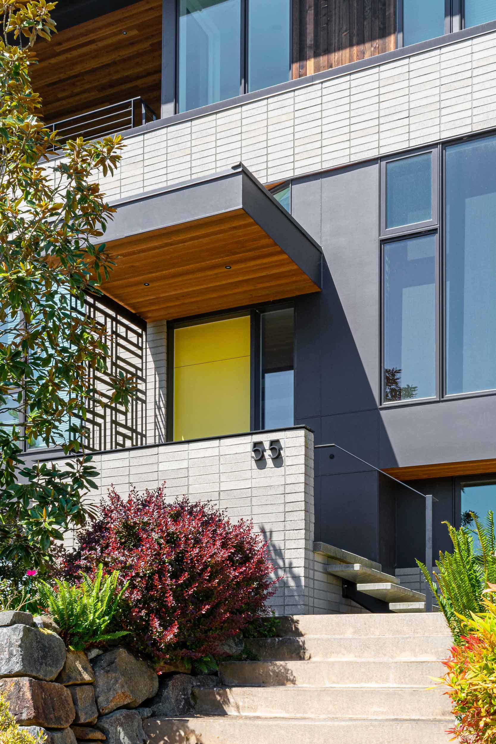 The entryway of this remodeled home was given a fresh makeover, with steps leading up to a metal screen and a bright yellow door.