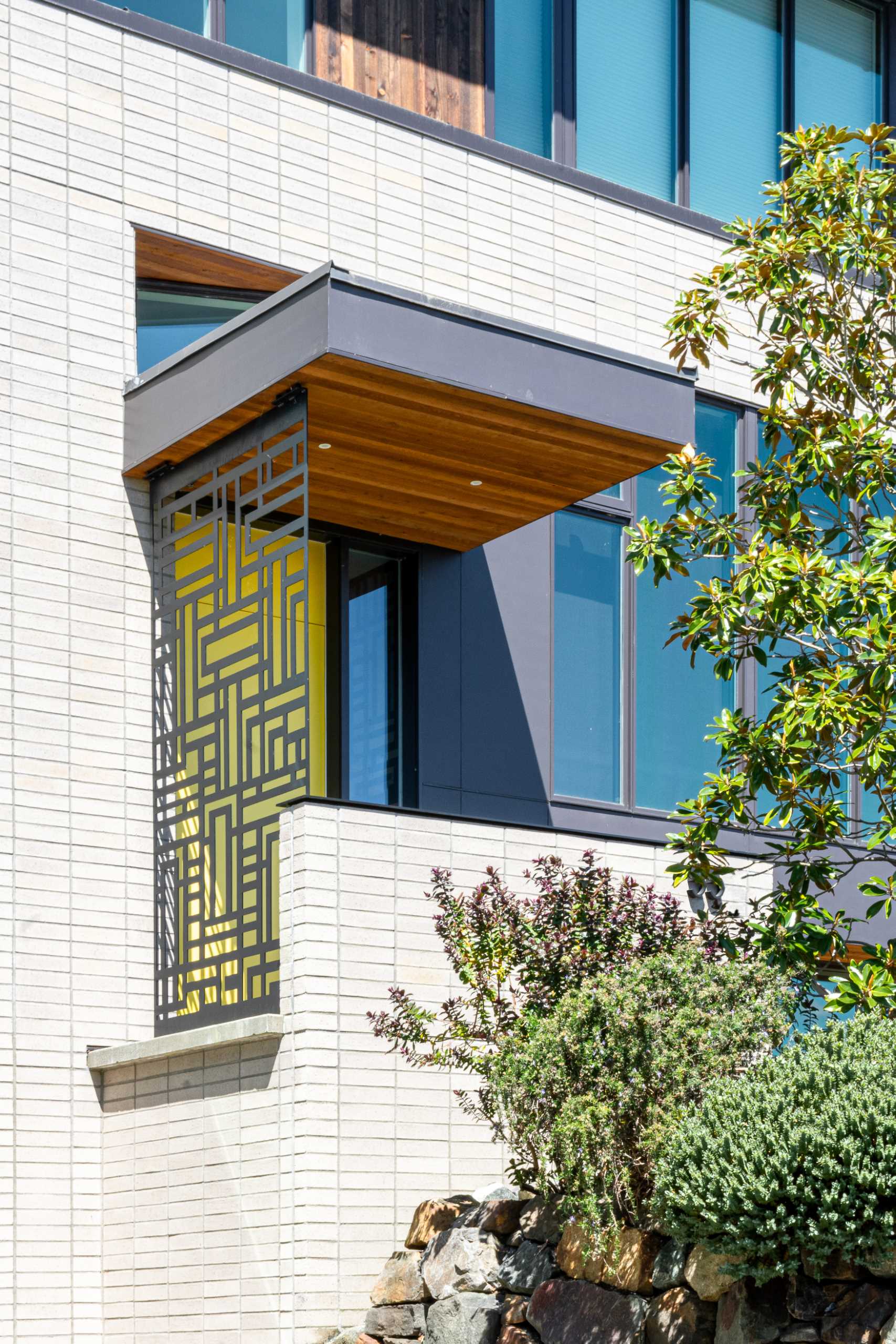 The entryway of this remodeled home was given a fresh makeover, with steps leading up to a metal screen and a bright yellow door.