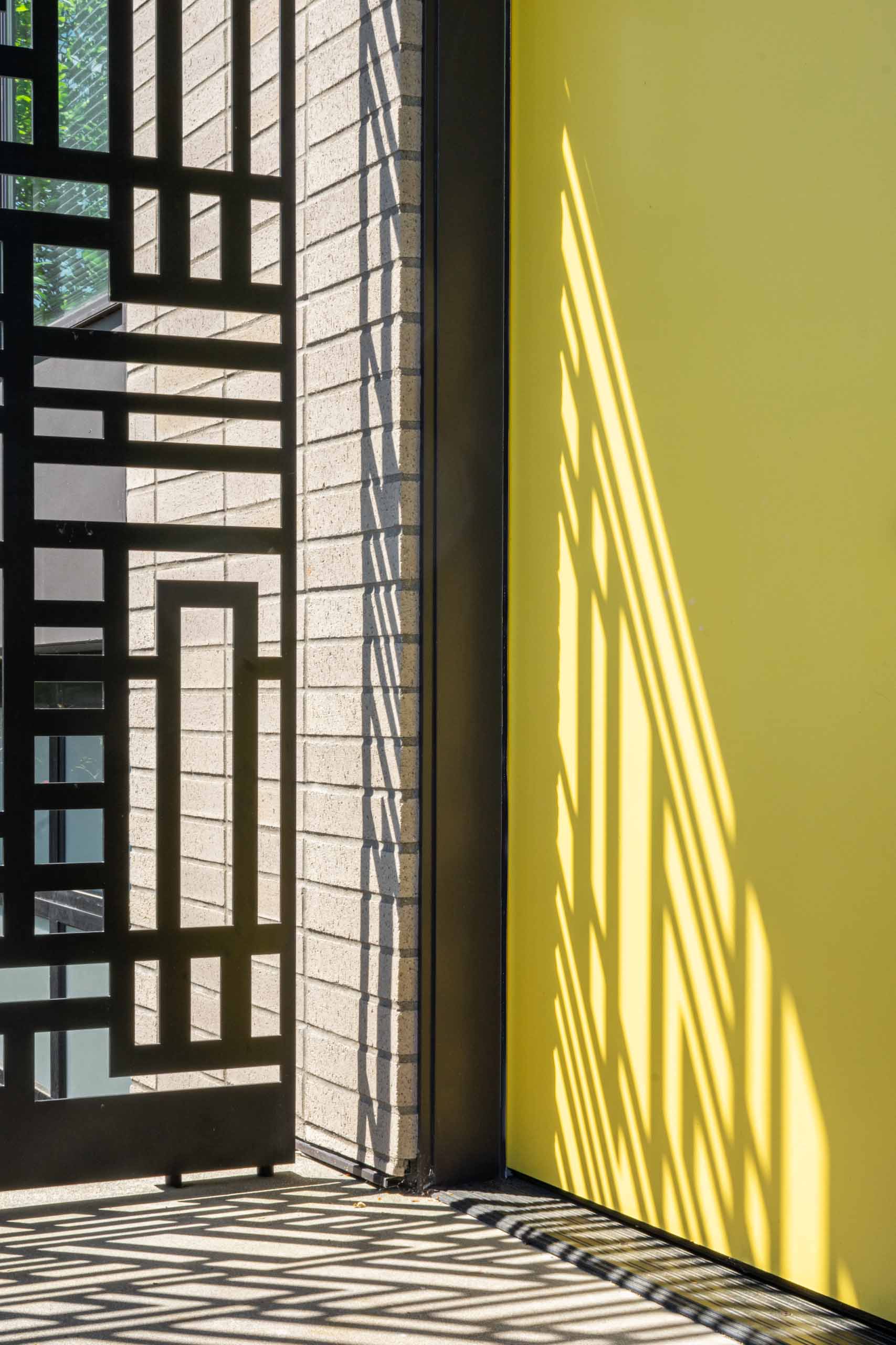 The entryway of this remodeled home was given a fresh makeover, with steps leading up to a metal screen and a bright yellow door.