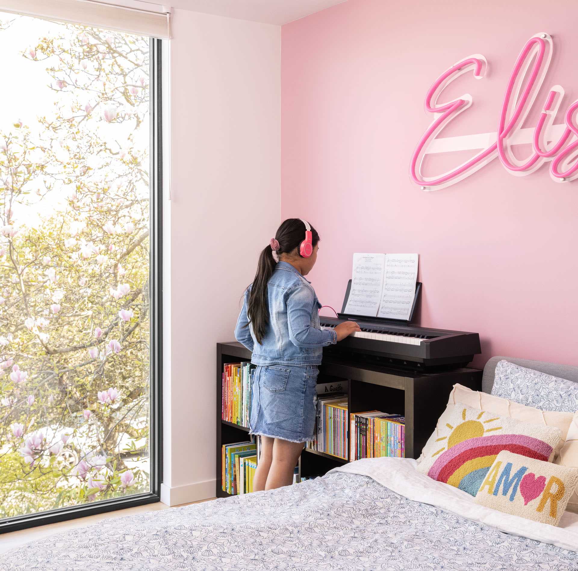 In a kid's bedroom, a pink accent wall with a neon sign creates a fun and colorful environment.