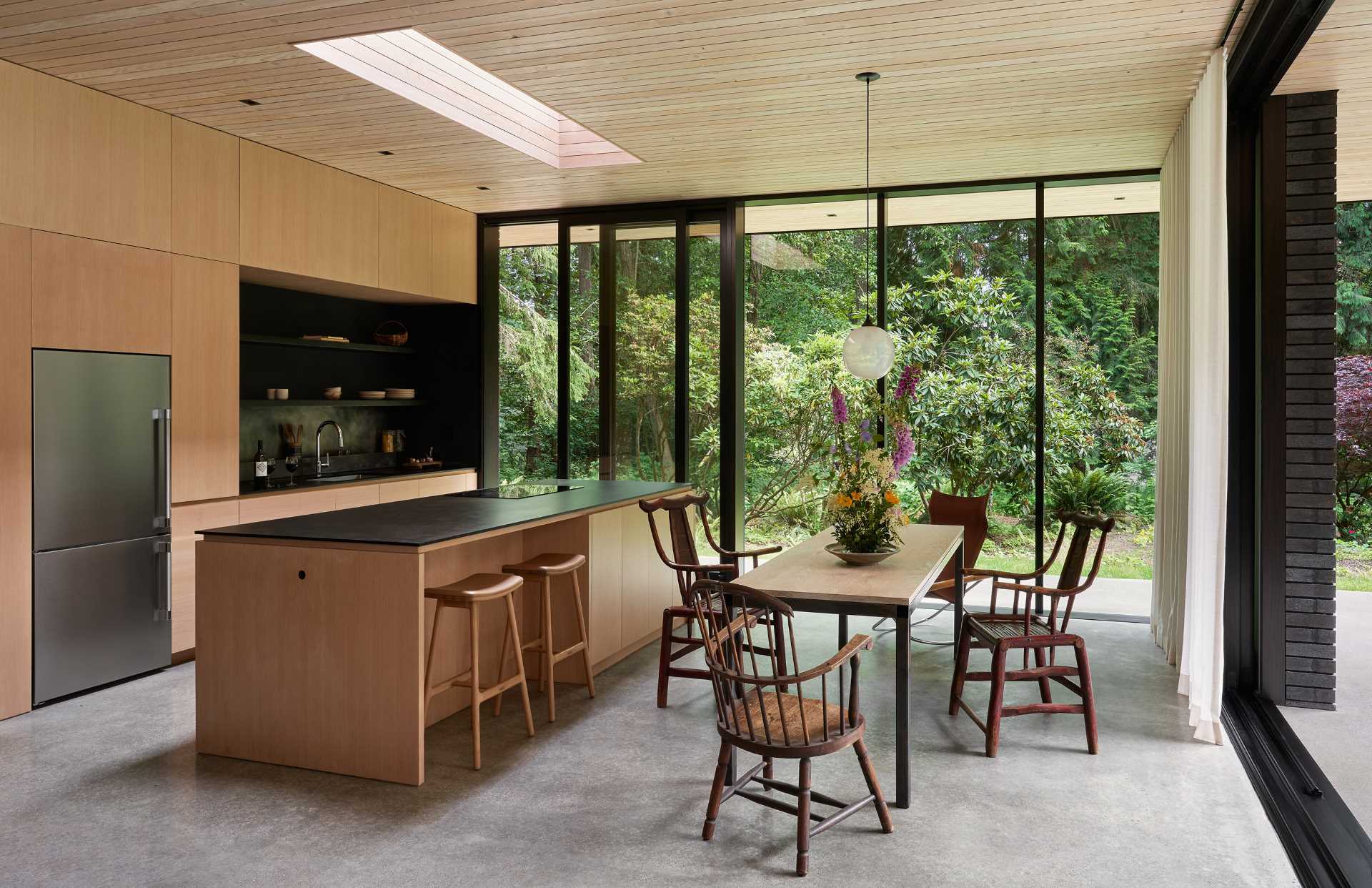 This modern kitchen features custom wood cabinets, dark countertops, and a custom blackened stainless steel backsplash.