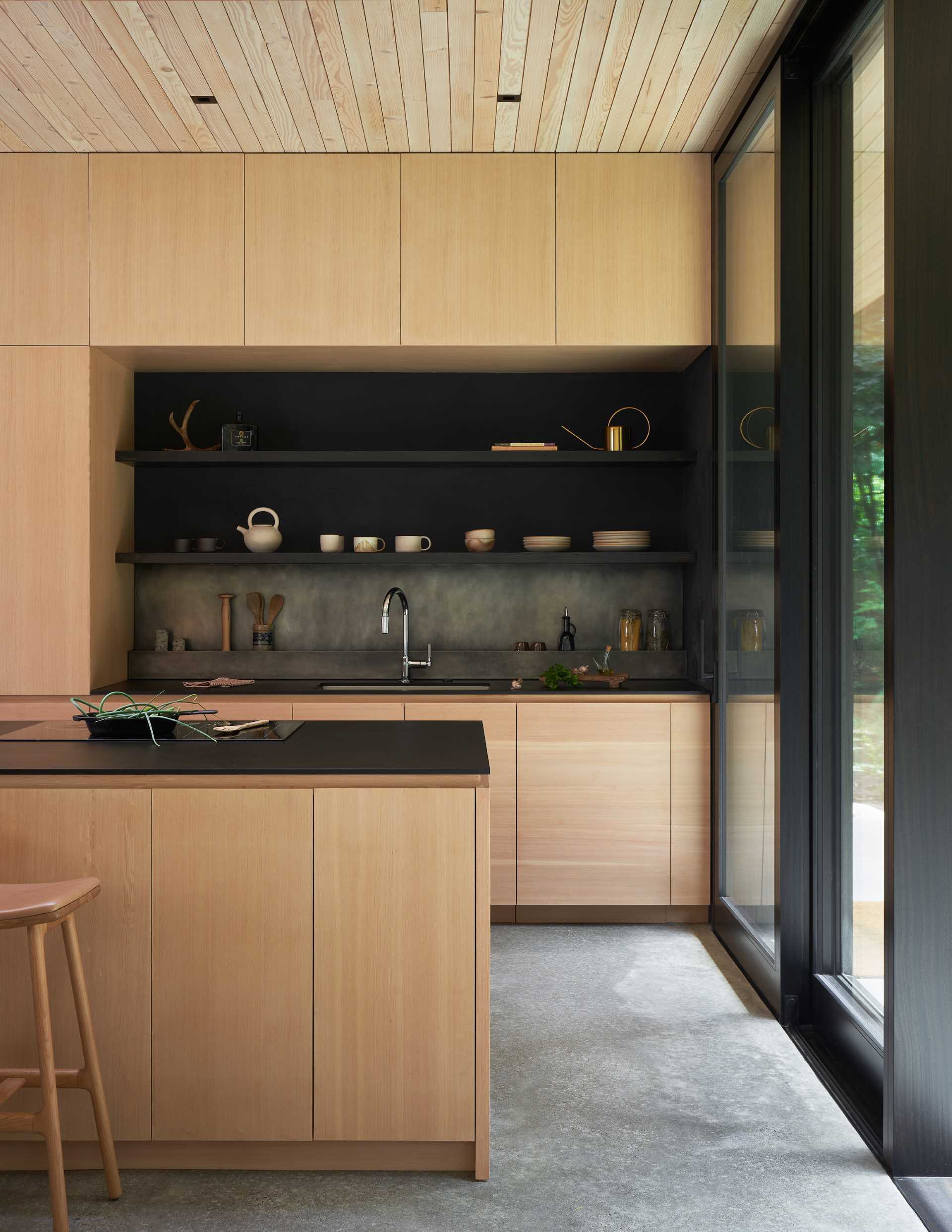 This modern kitchen features custom wood cabinets, dark countertops, and a custom blackened stainless steel backsplash.