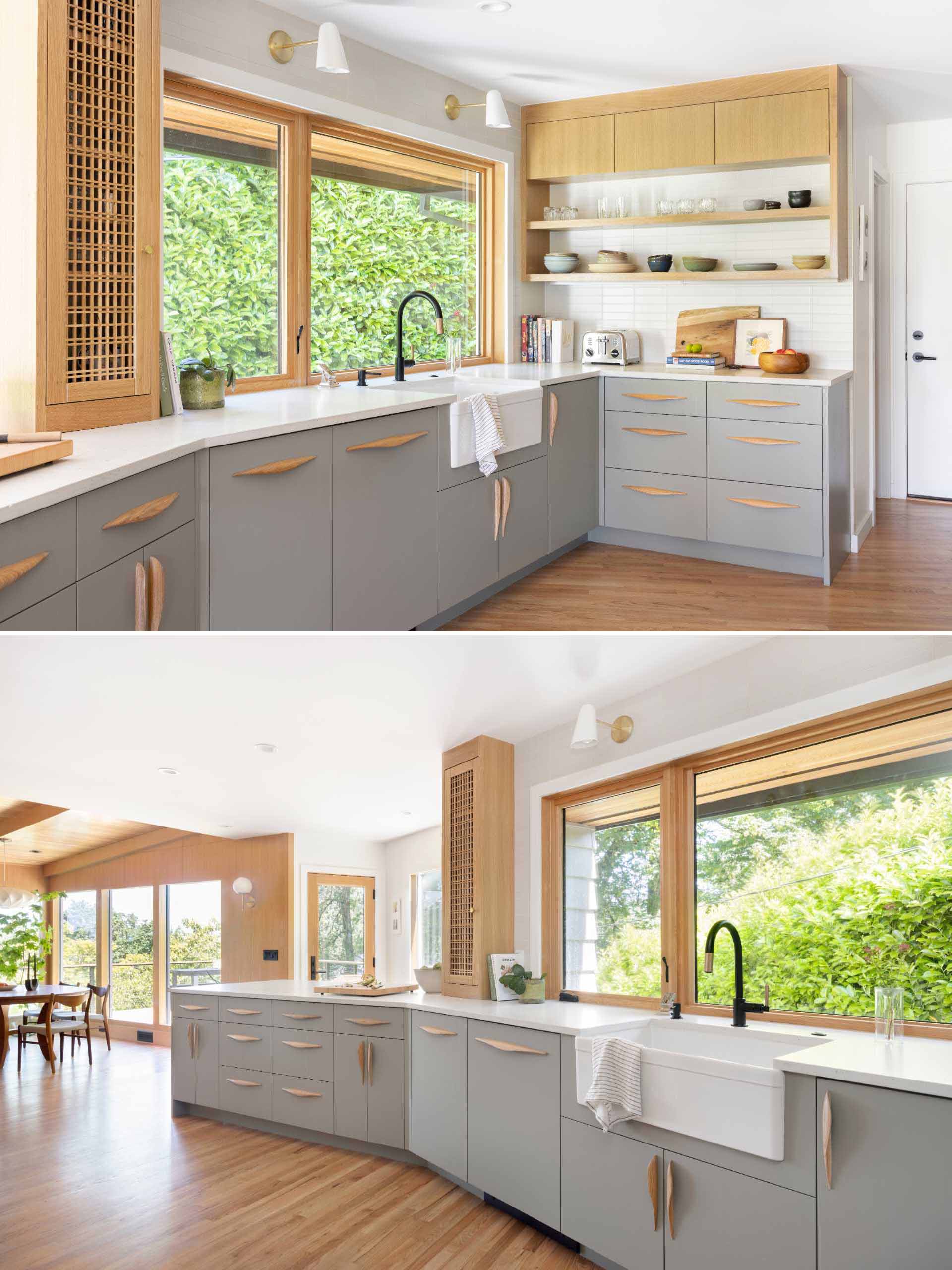 This new open kitchen includes a grey peninsula, grey cabinets, wood details, white countertops, and a tiled backsplash by the stove.